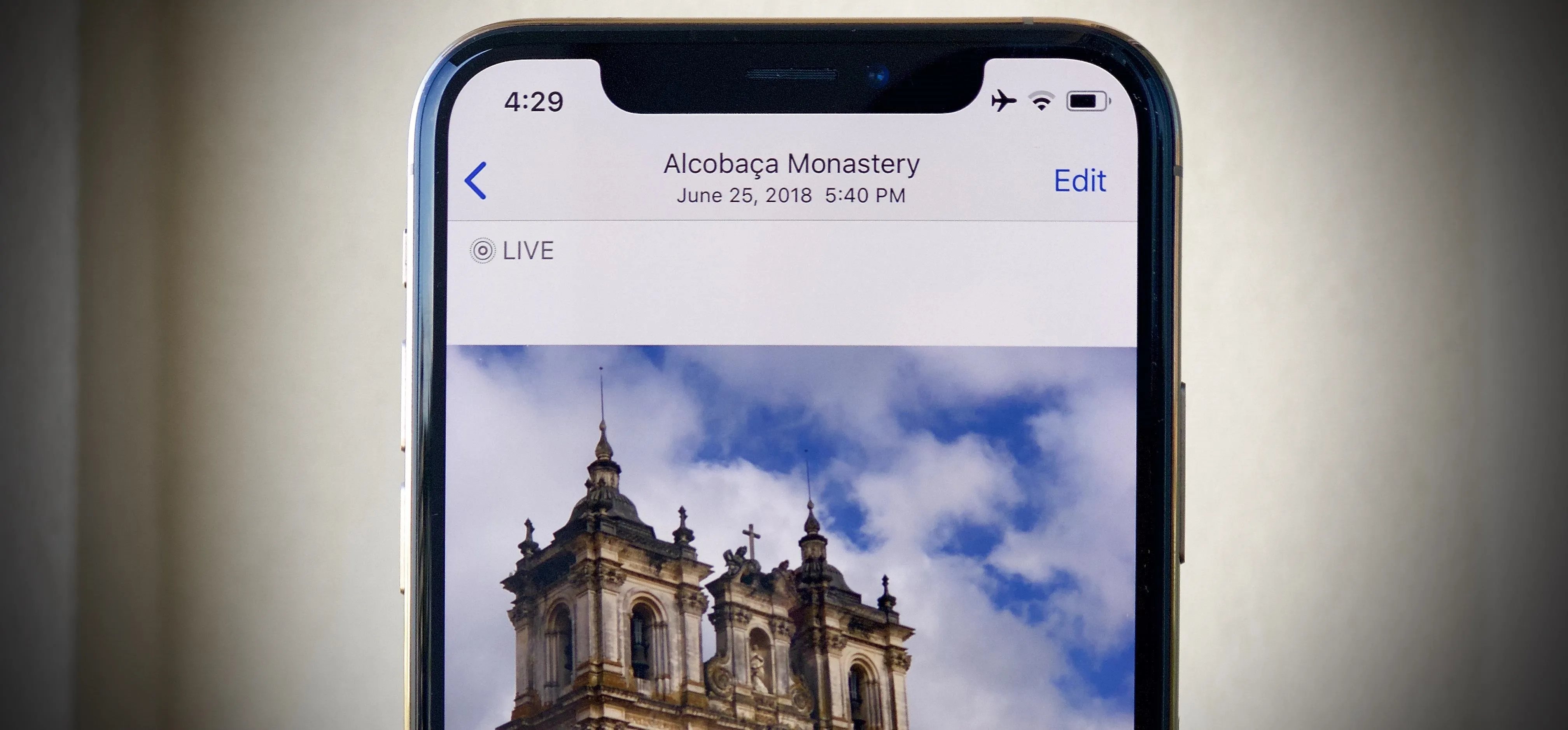 Smartphone displaying an image of a historical building under a cloudy sky.