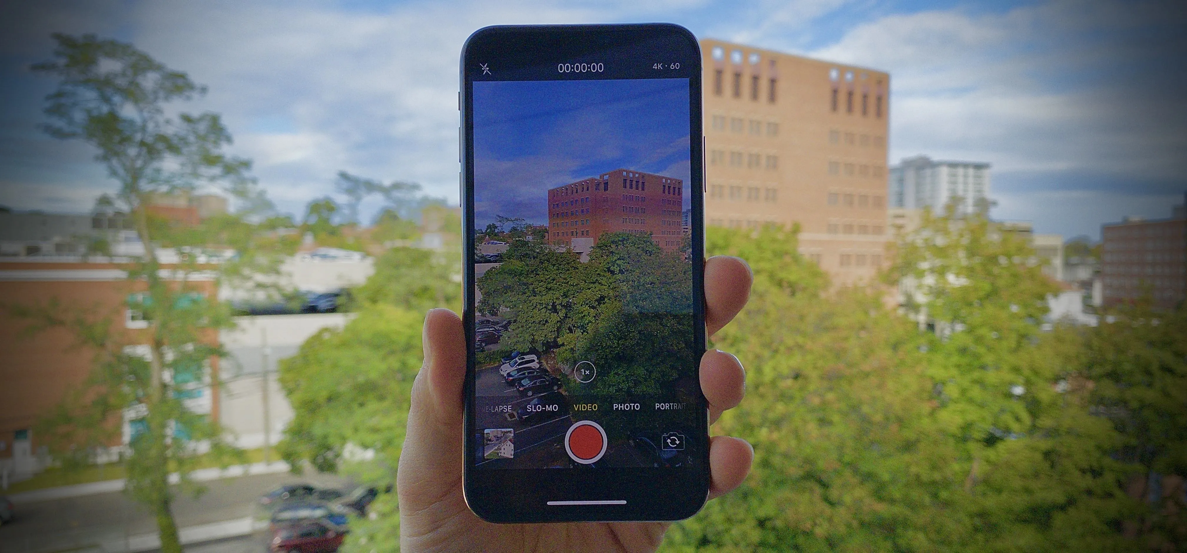 Person holding a smartphone displaying a video recording of an outdoor scene.