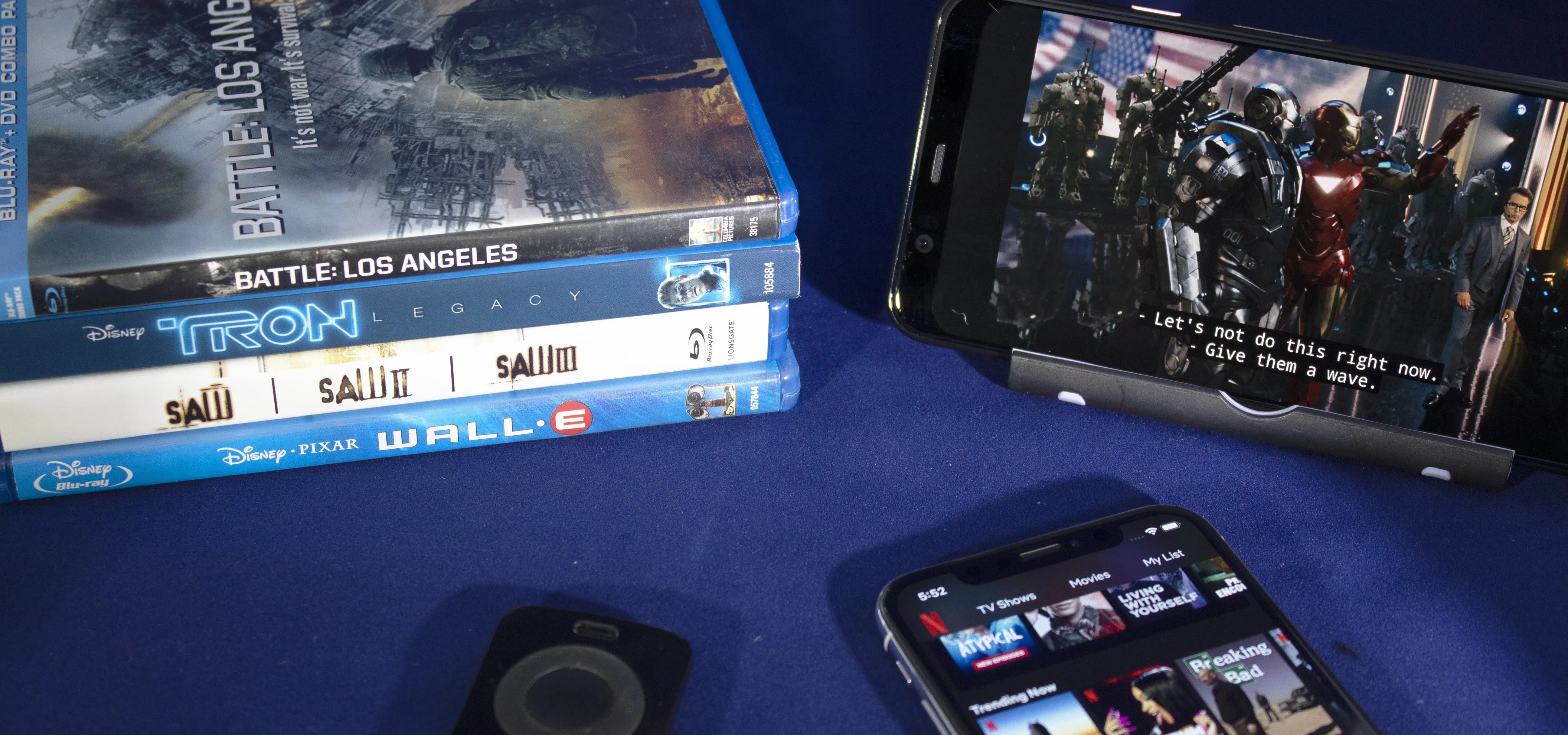 Blu-ray movies and a smartphone displaying a film scene.