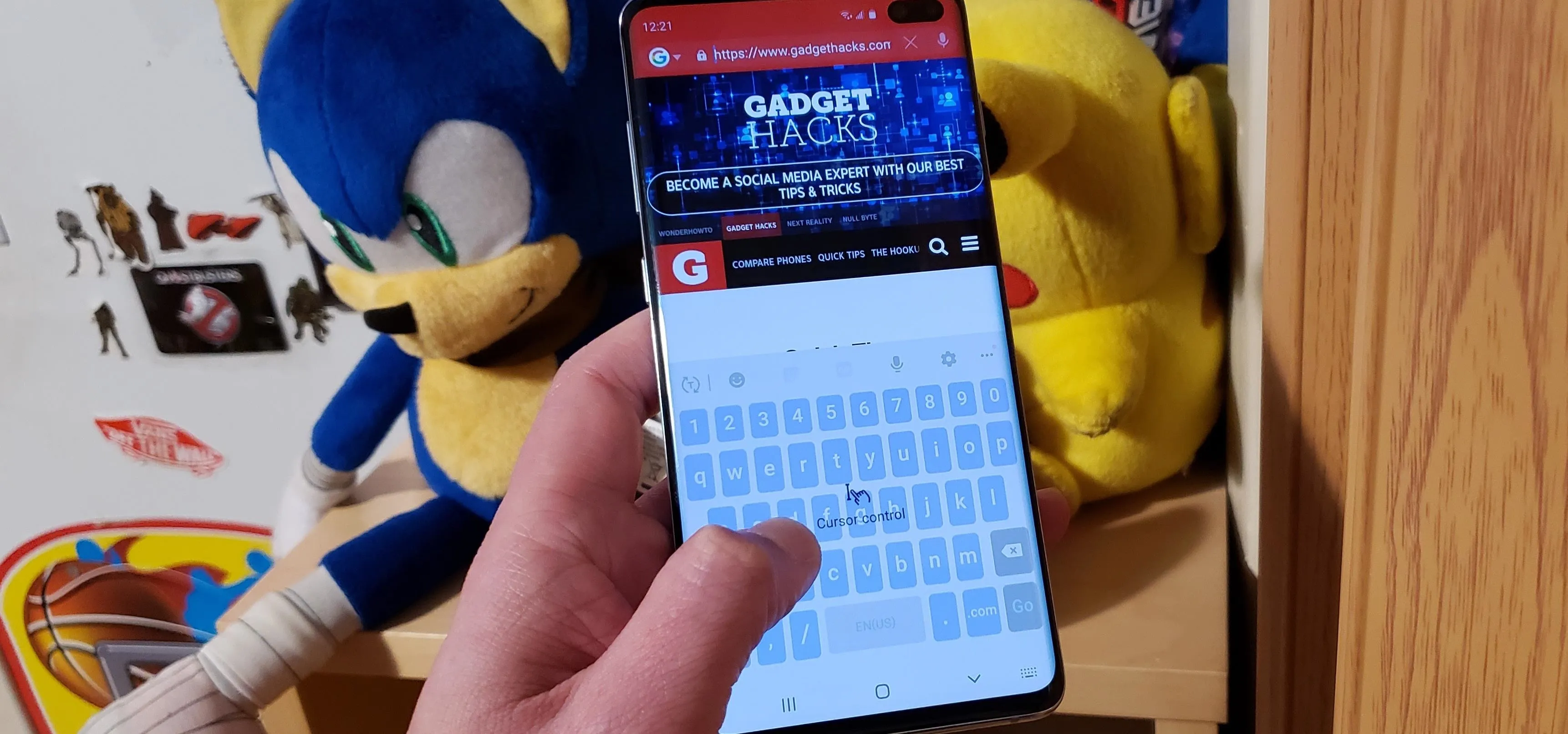 Person using a smartphone with gaming content on the screen, alongside plush toys in the background.