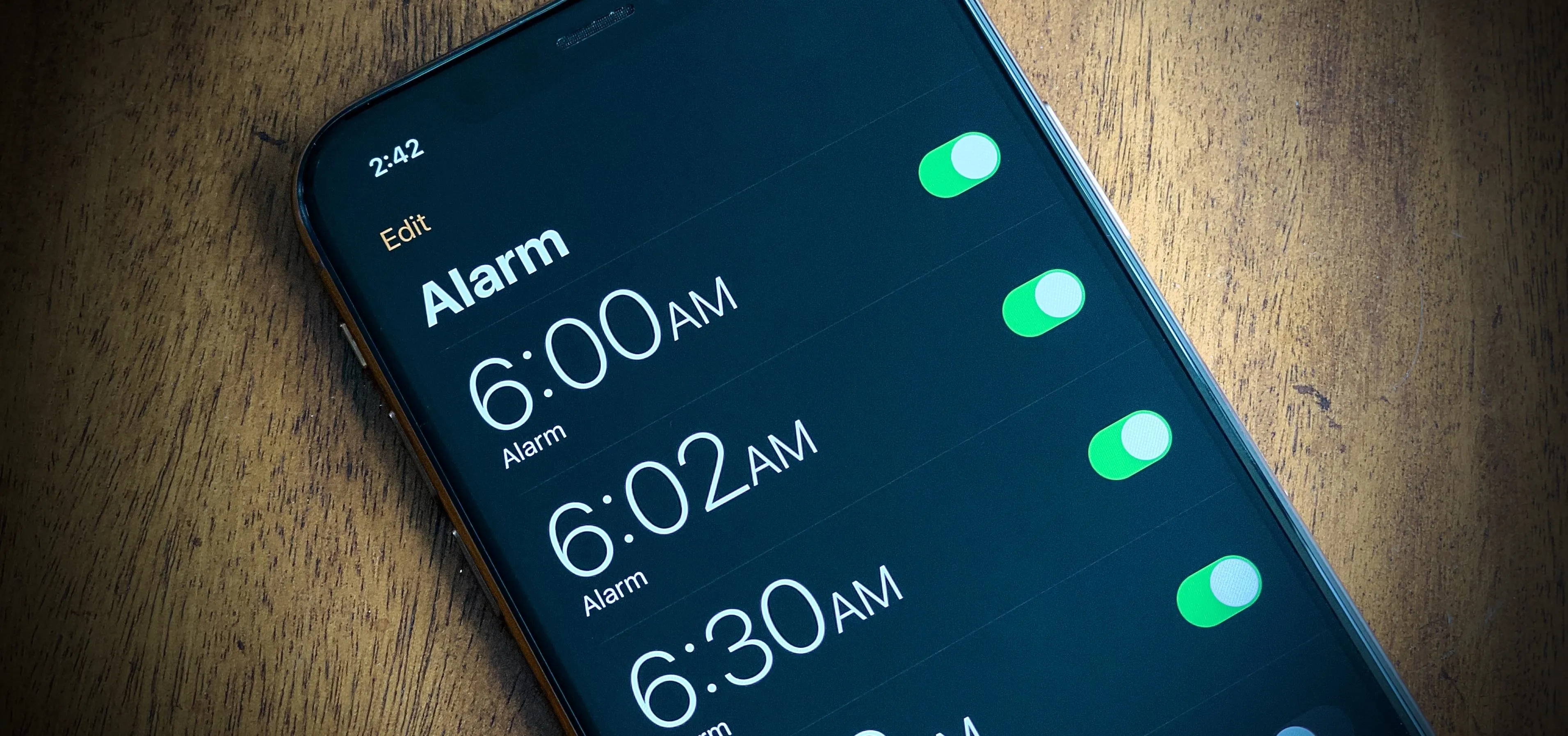 Alarm settings on a smartphone showing 6:00 AM, 6:02 AM, and 6:30 AM with toggles enabled.