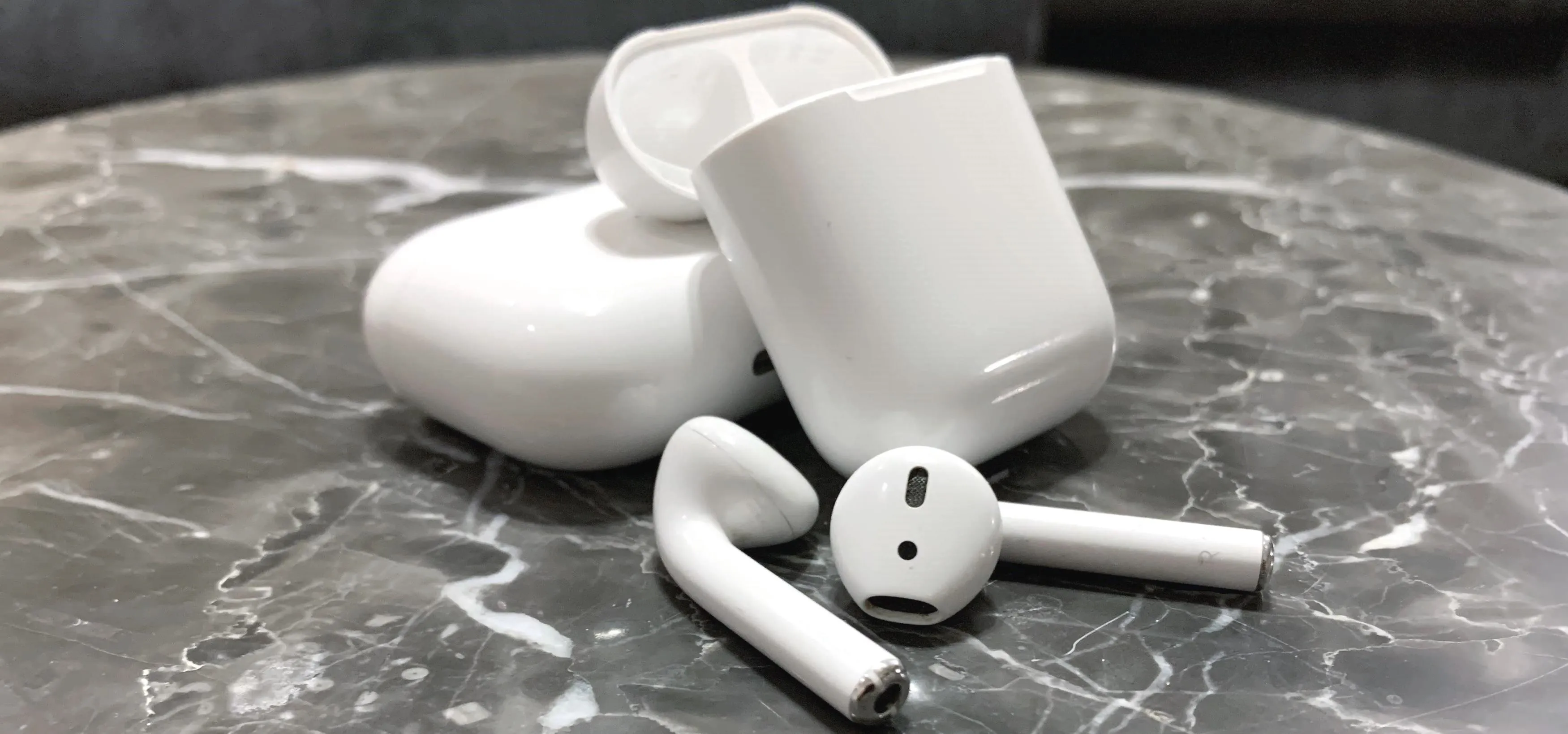 Wireless earbuds and charging case on a marble surface.