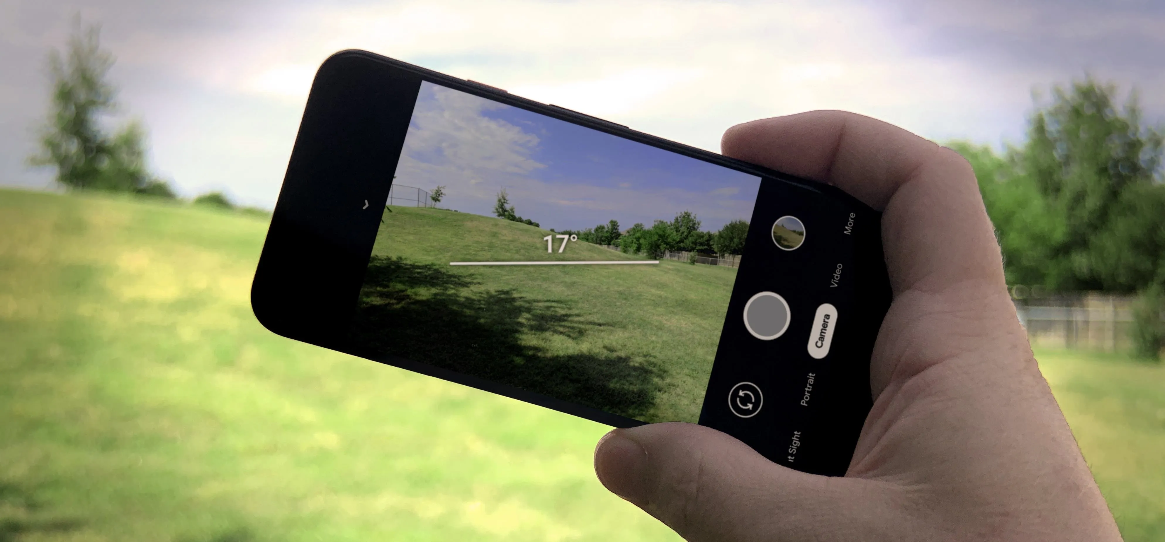 Person holding smartphone to capture landscape photo.