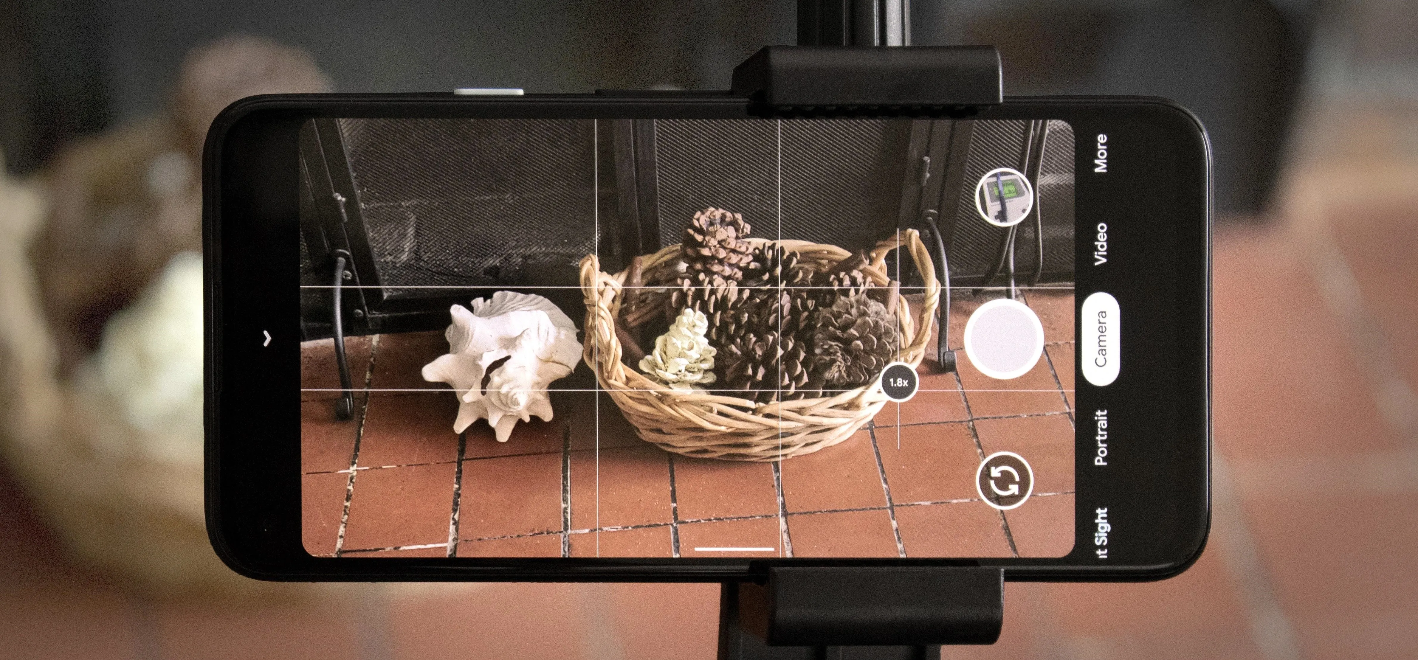 A smartphone camera displaying a basket of pinecones and shells.