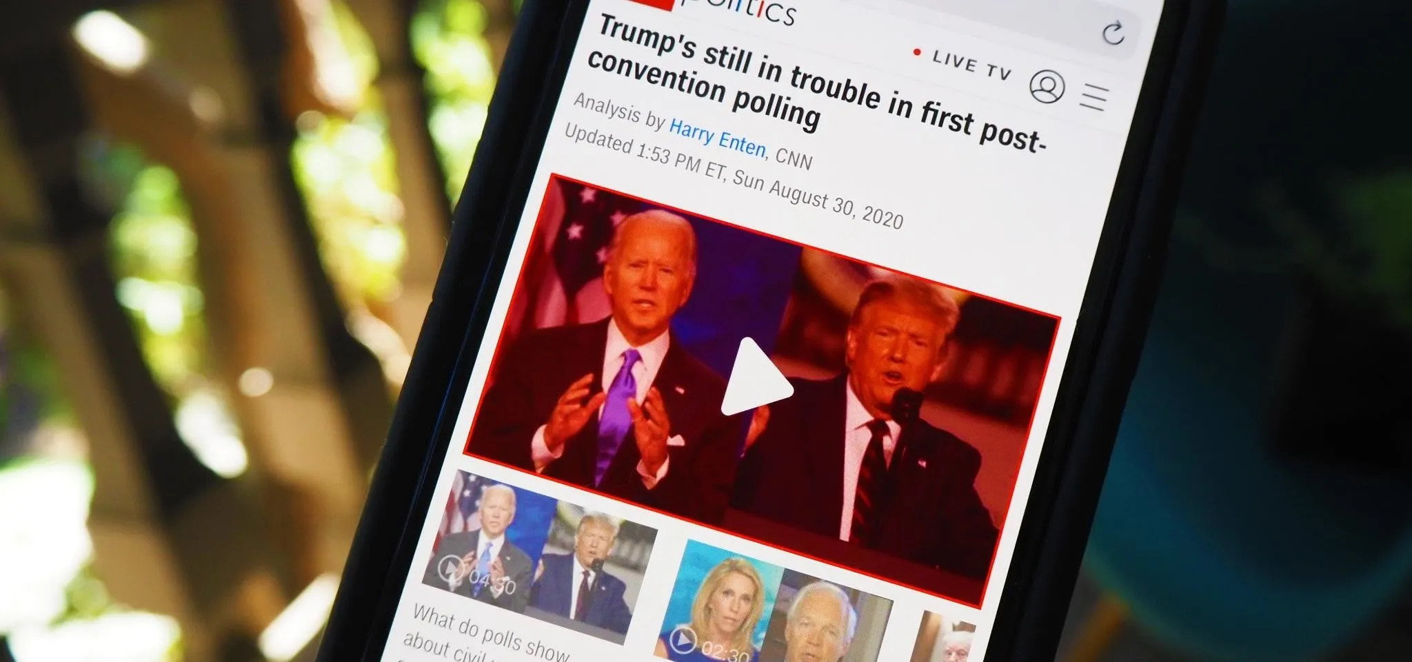 News article on a mobile device featuring video of Joe Biden and Donald Trump.