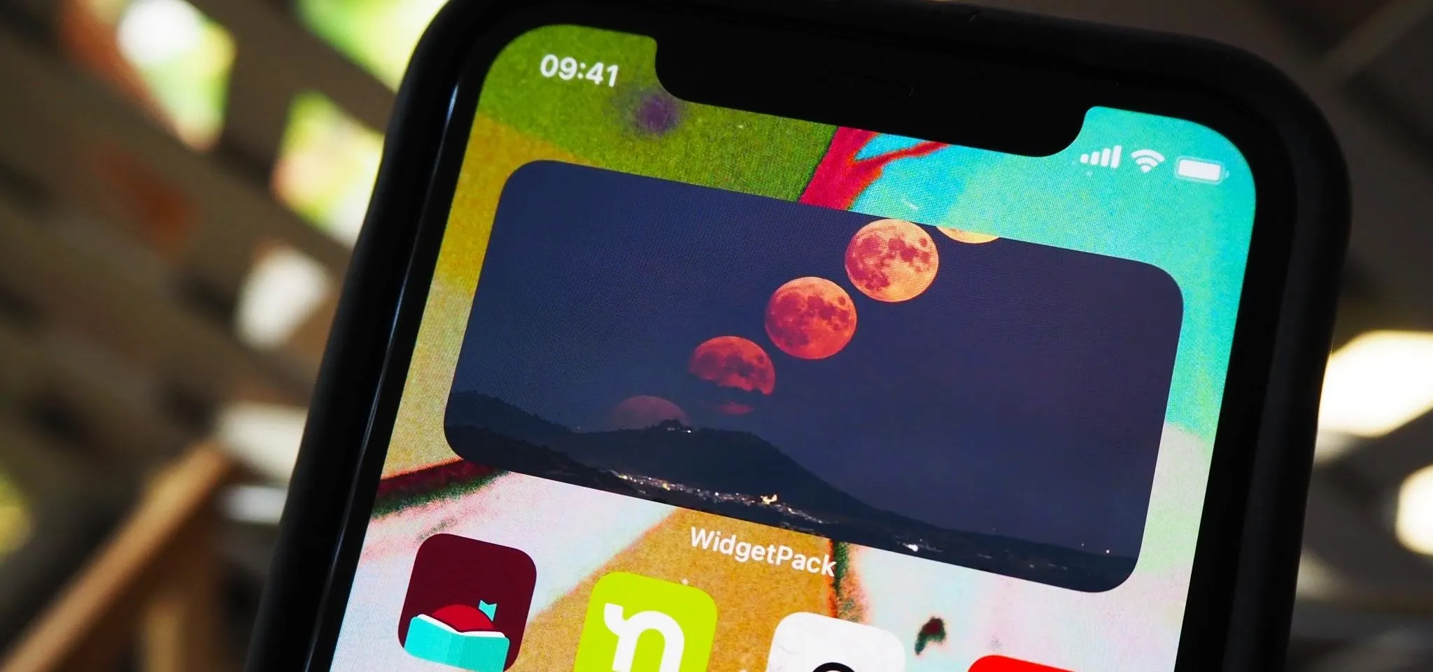 Phone screen displaying a lunar phase wallpaper with various app icons visible.