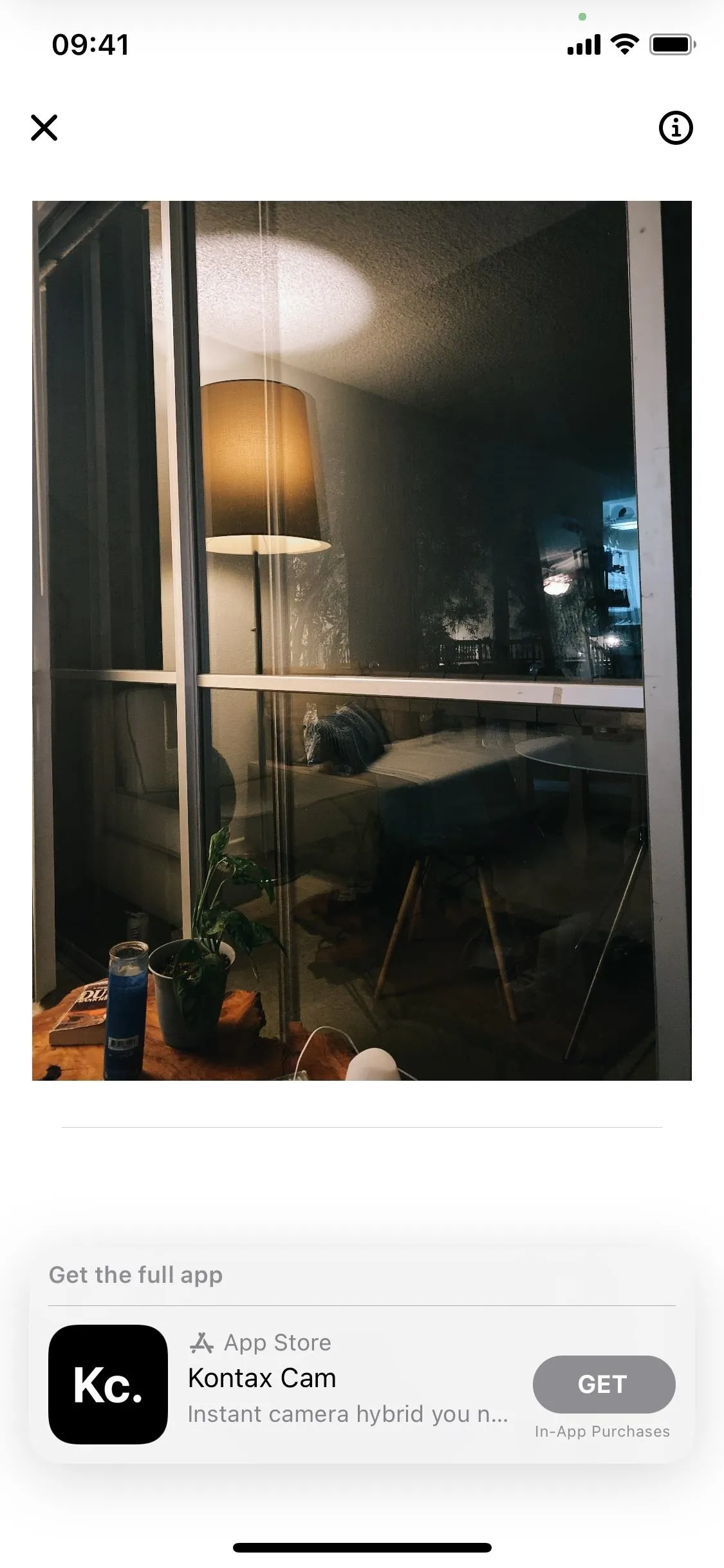 A warmly lit room with a lamp and window reflections.