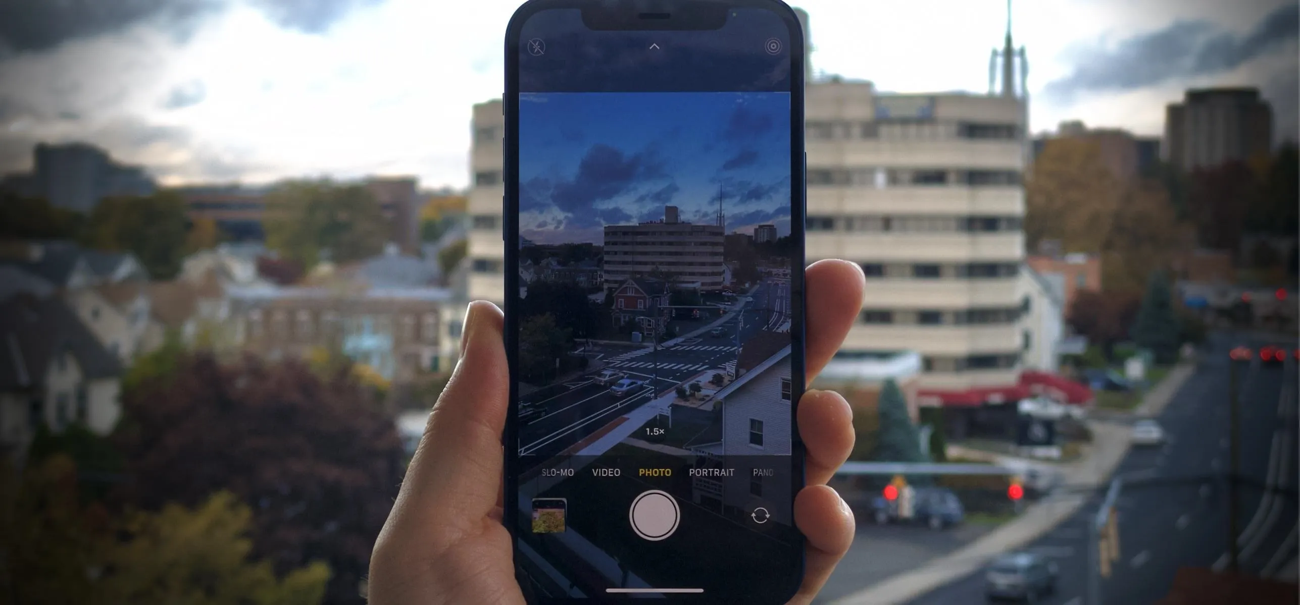 A hand holding a smartphone with a photo of a cityscape on the screen.