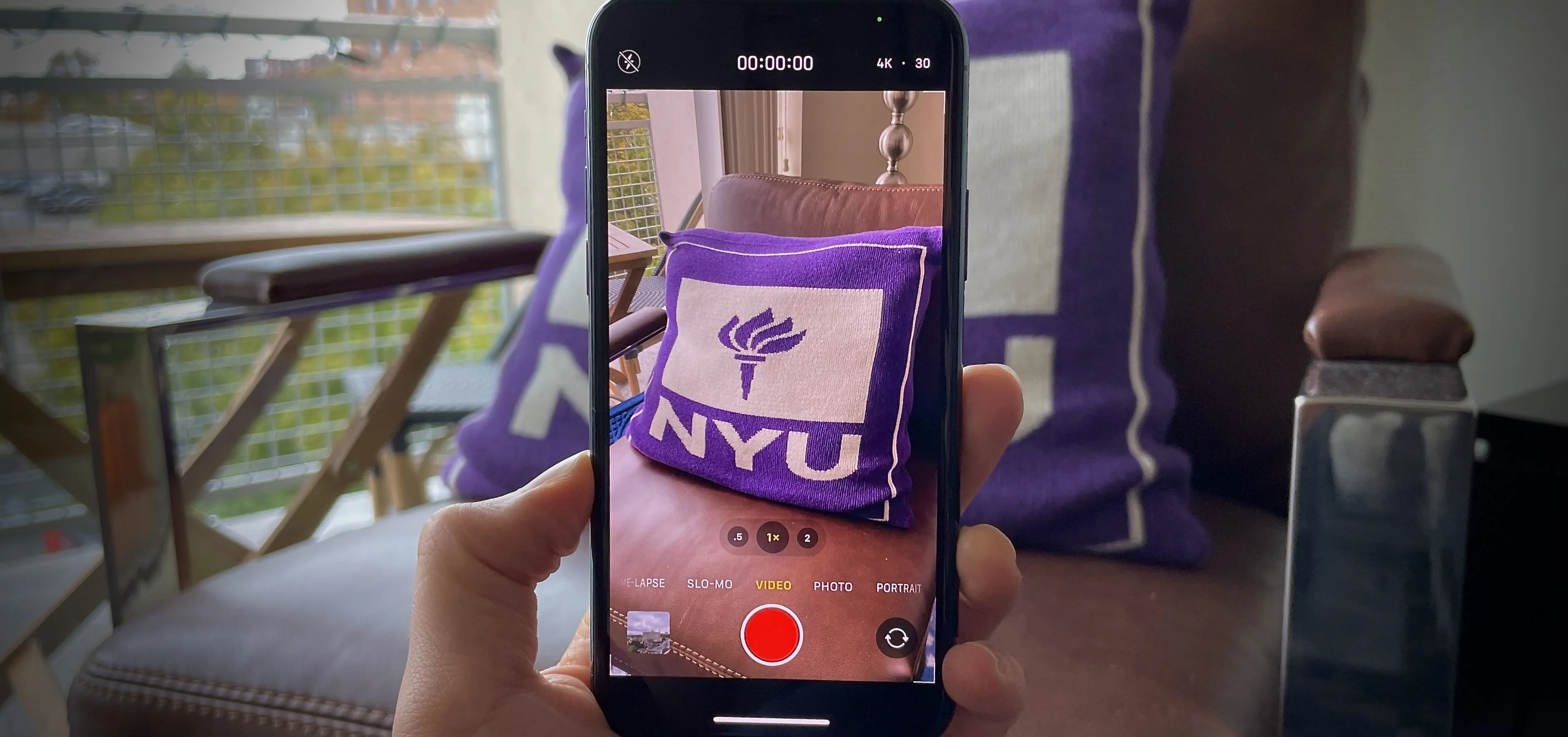 Person holding a smartphone showing a purple NYU bag.
