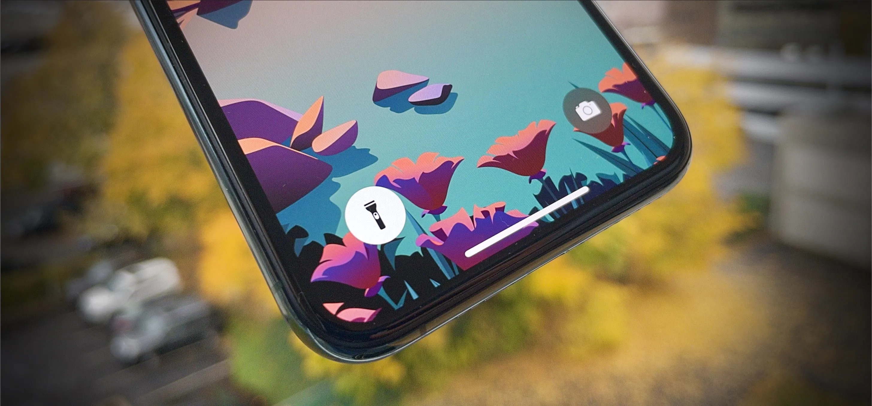 Smartphone with vibrant abstract wallpaper in a natural setting.