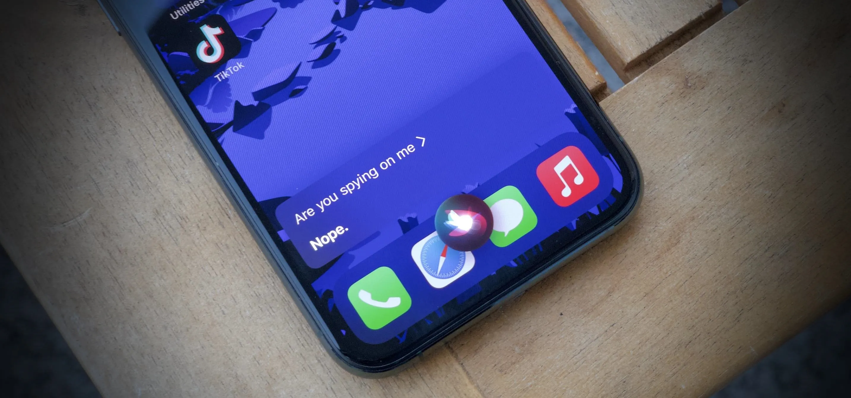 Smartphone screen displaying app icons, including TikTok and music apps, on a wooden surface.