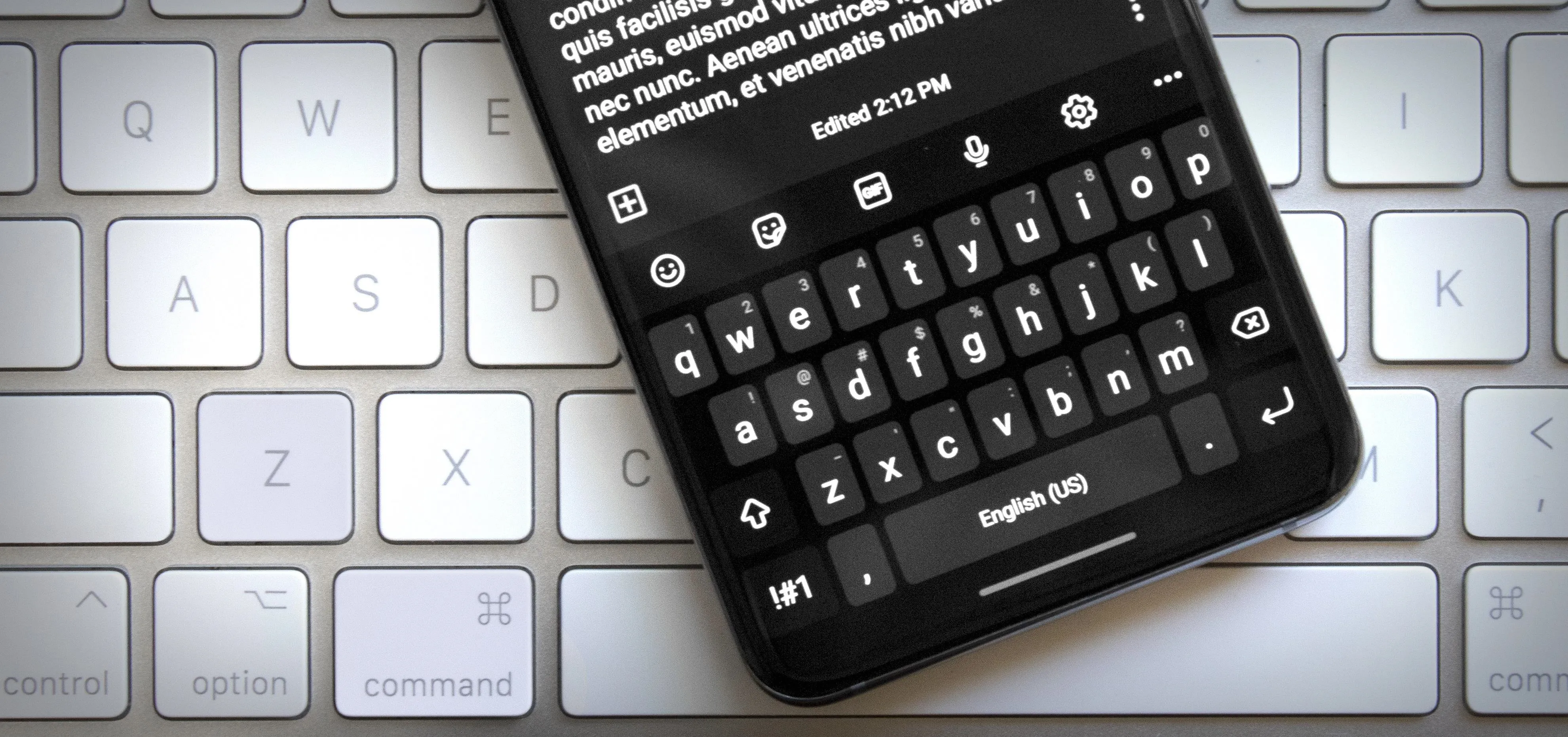 Smartphone on a laptop keyboard displaying text on the screen.