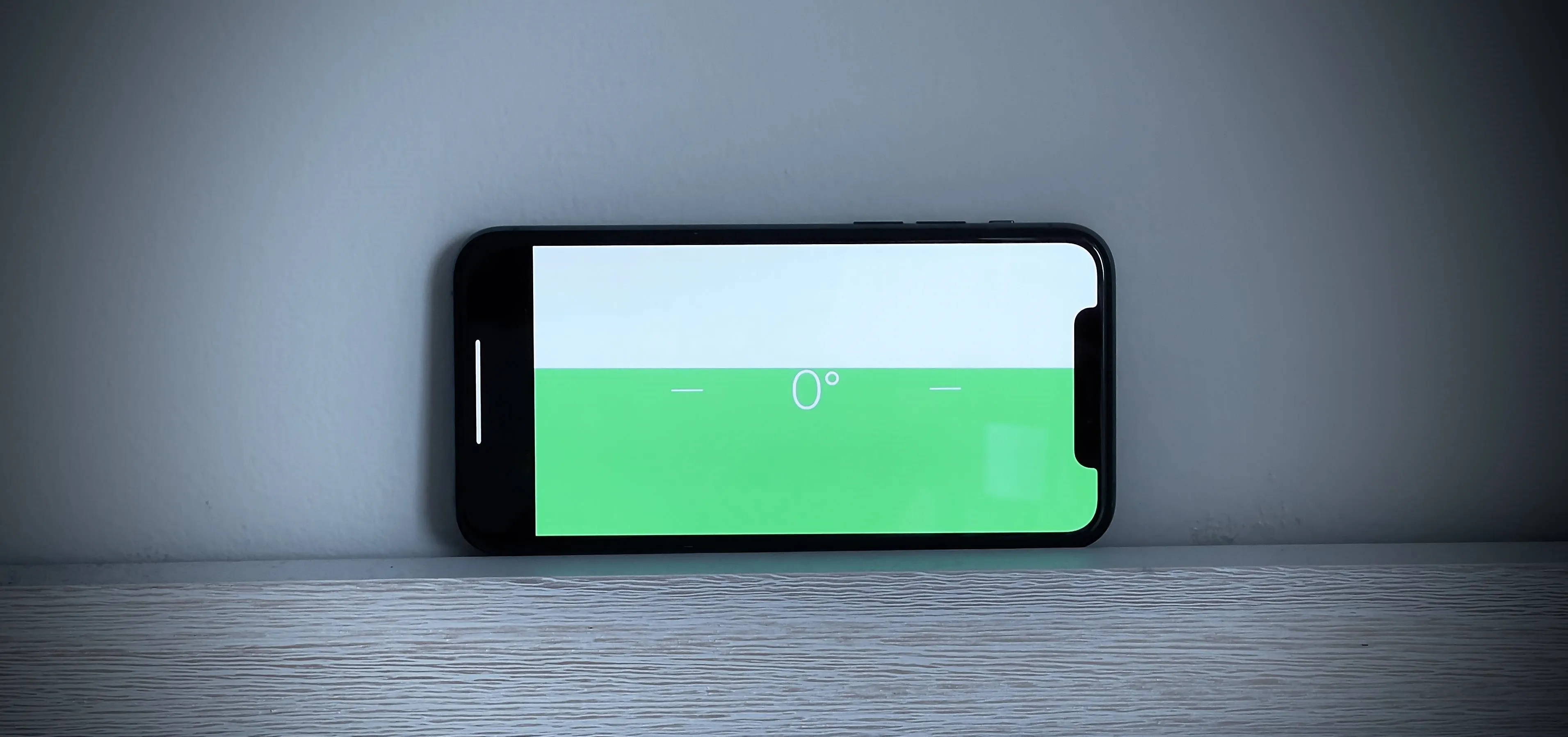 Smartphone displaying a green interface on a wooden surface.