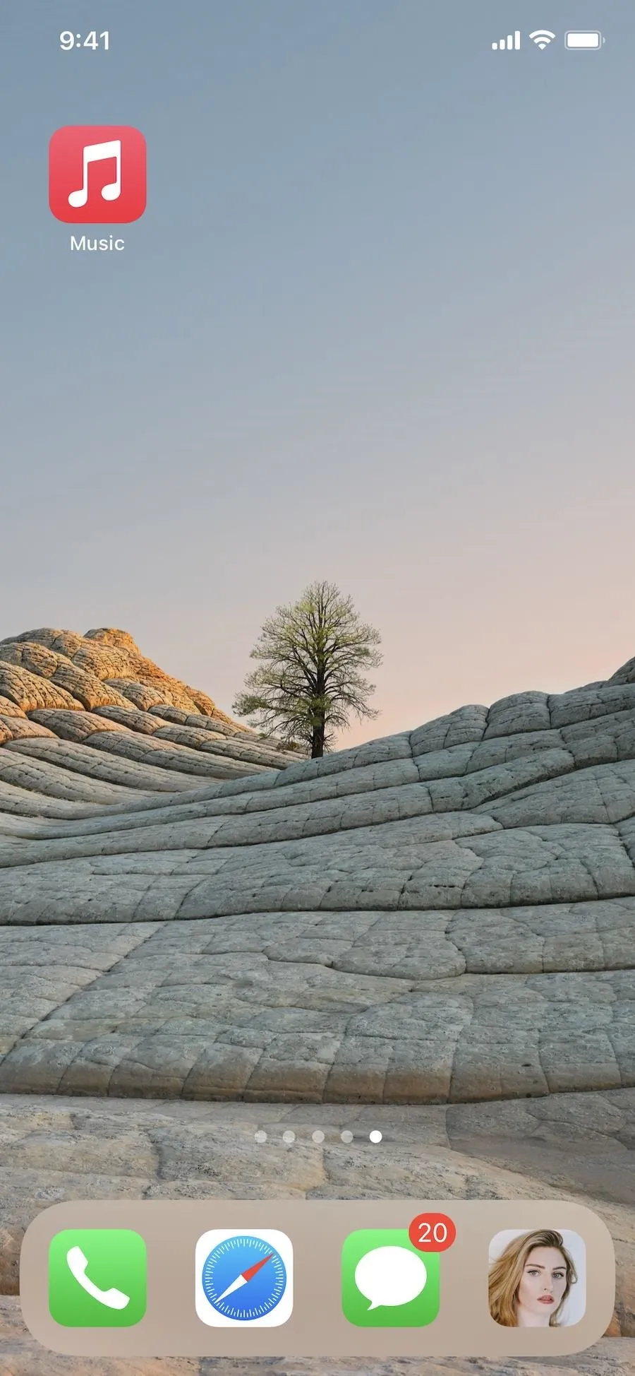 A serene landscape featuring a lone tree atop layered rock formations under a clear sky.