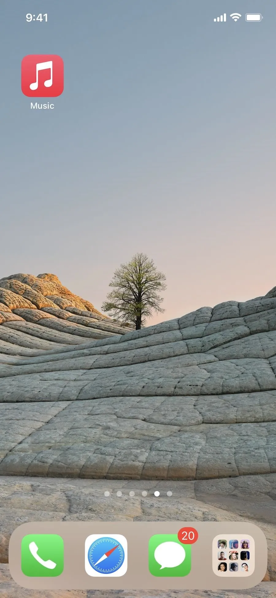 A smartphone screen displaying a minimalist landscape wallpaper with a tree among curved stone formations.