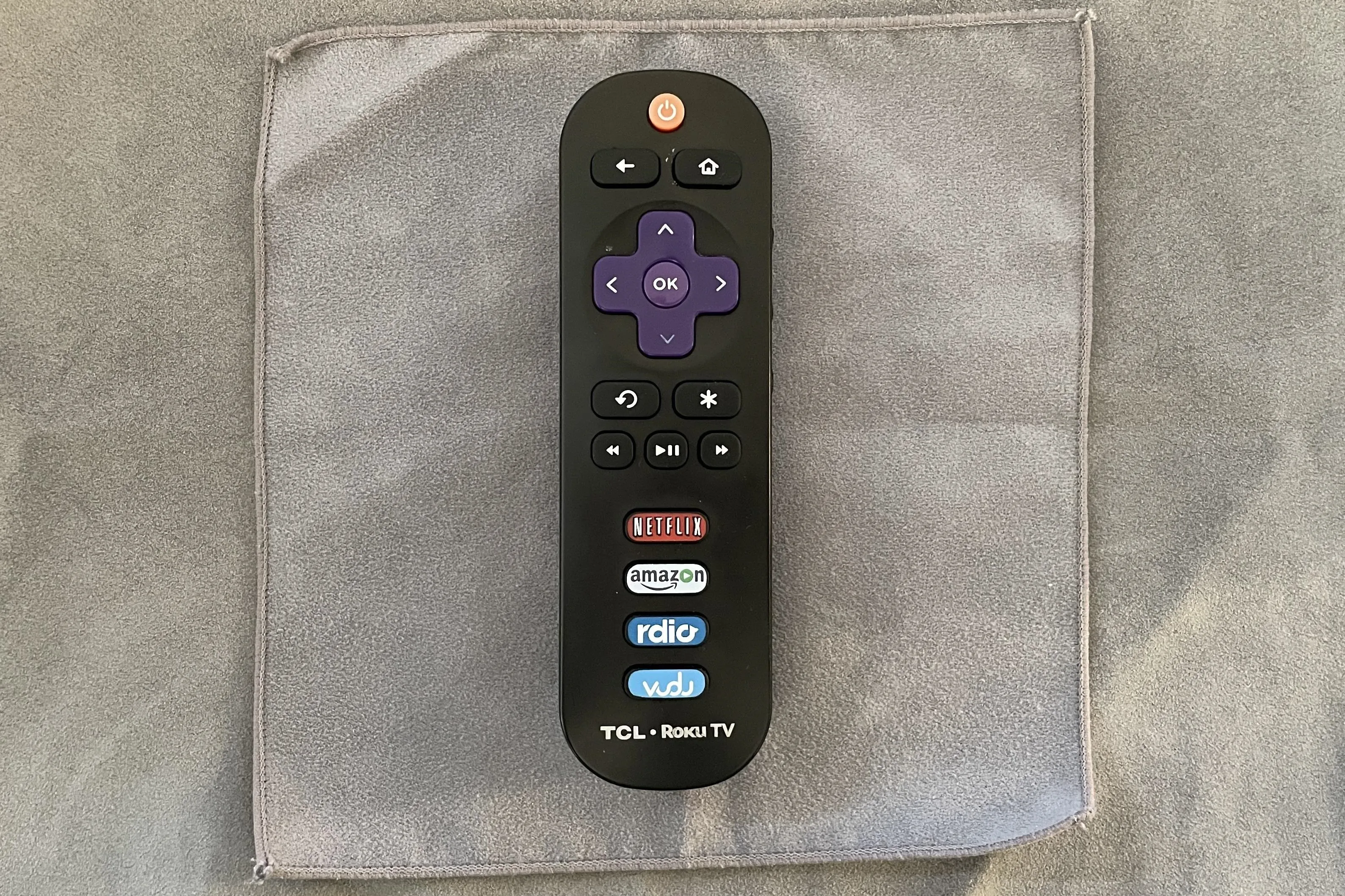 Remote control for a TCL Roku TV on a gray background.