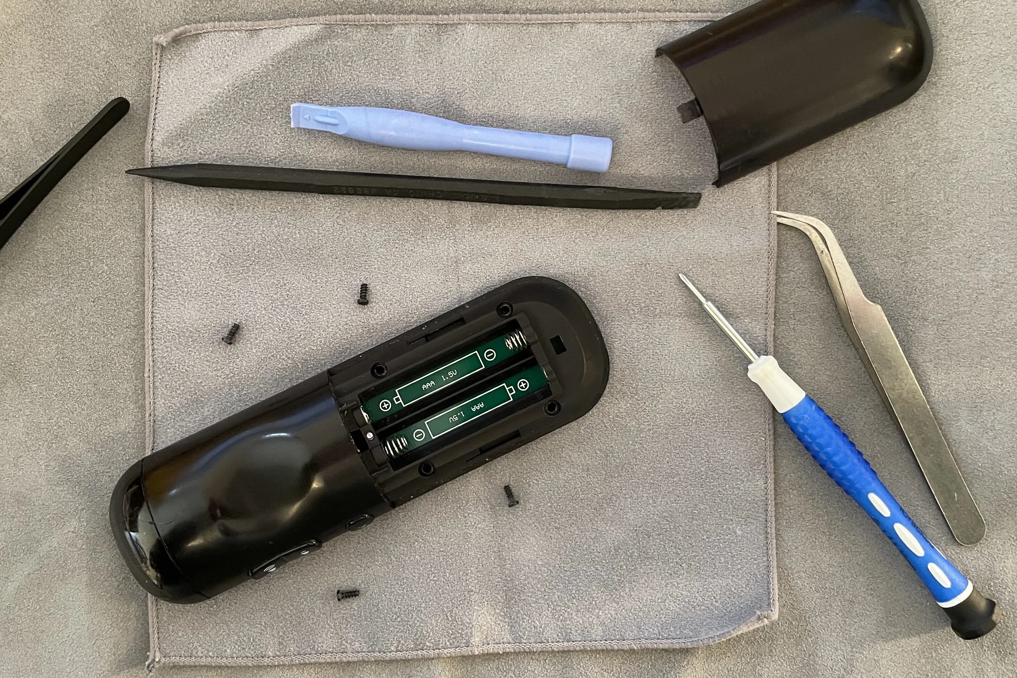 Screwdriver and tools for electronic device repair with batteries displayed.