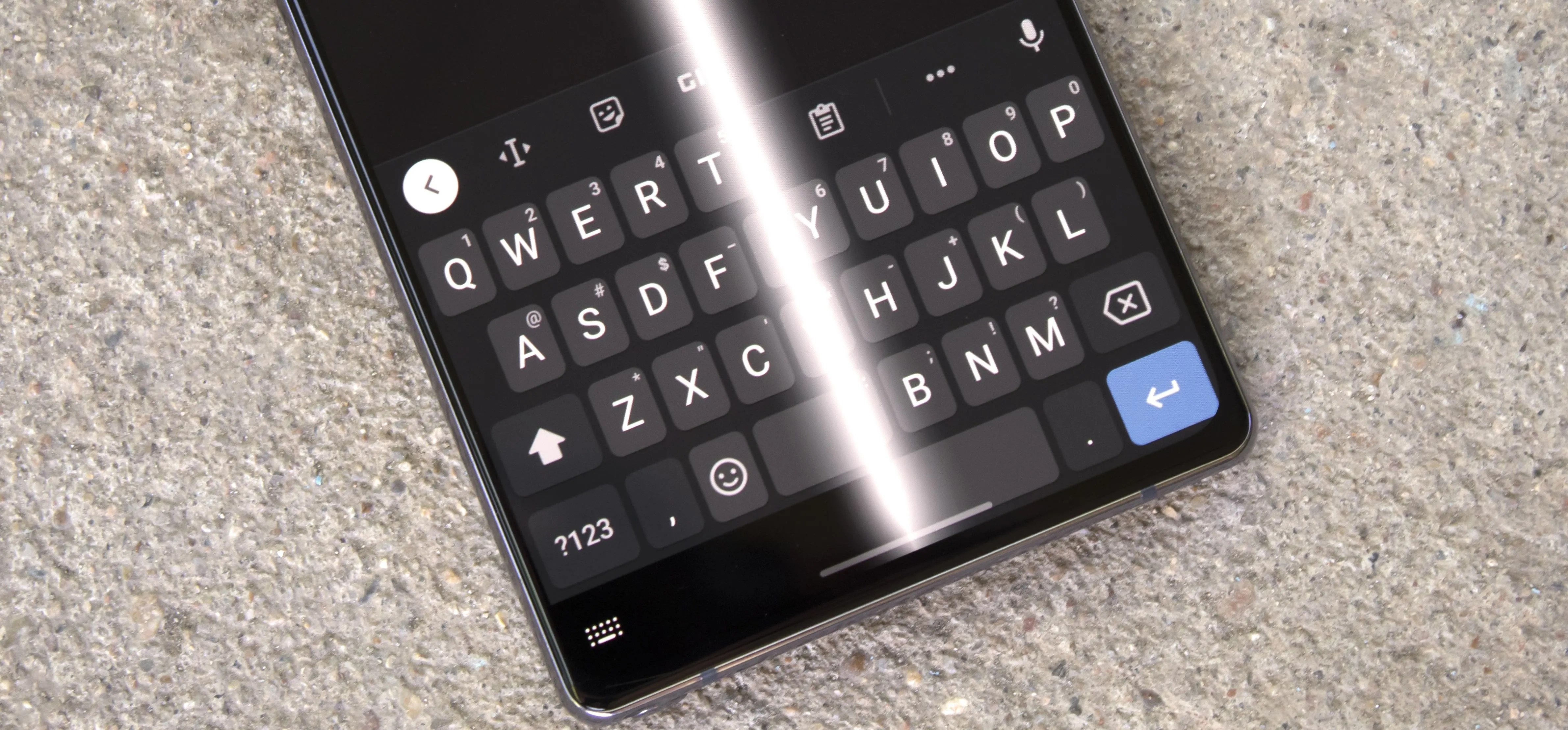 Smartphone keyboard viewed from above on a textured surface.