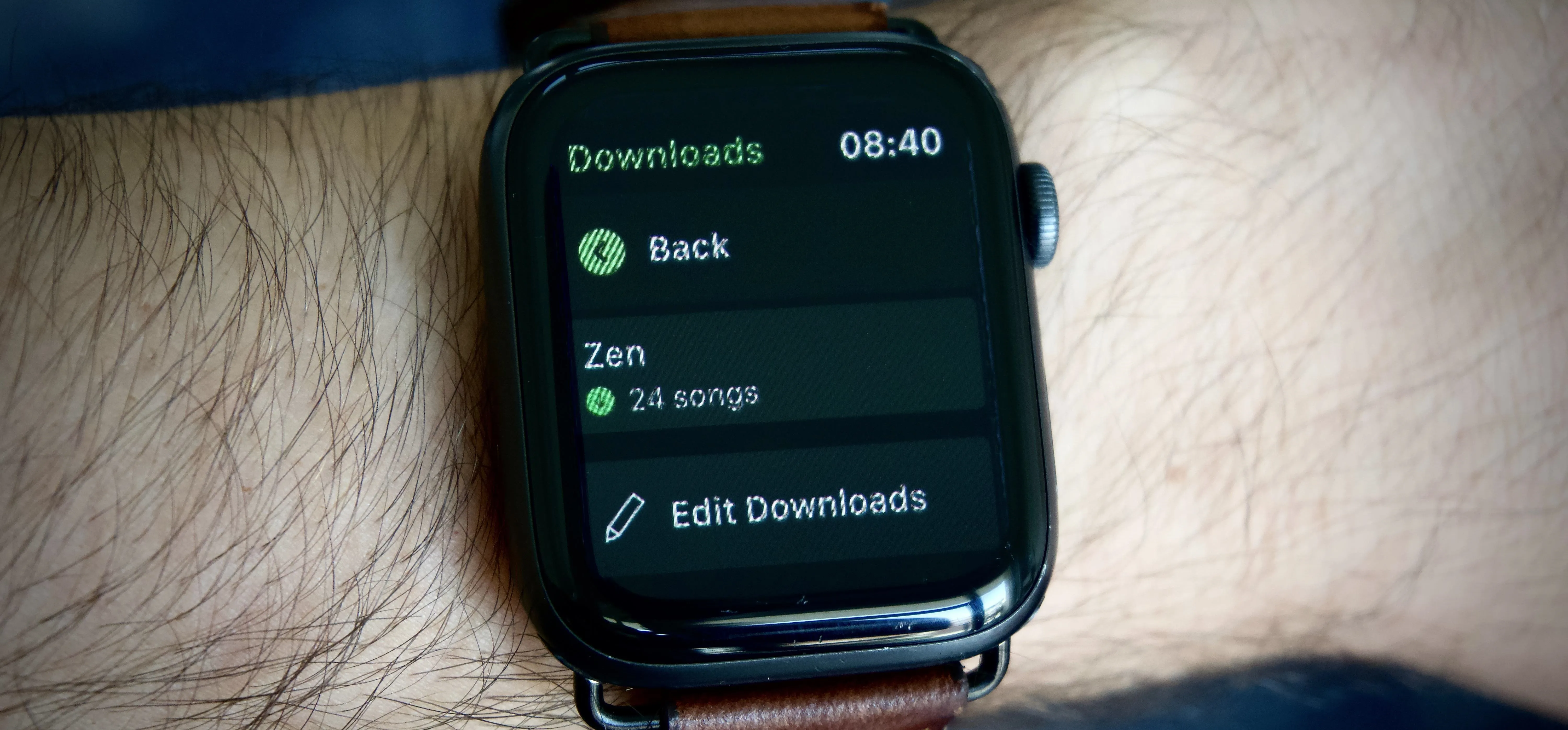 Smartwatch displaying a media player interface on a wrist.