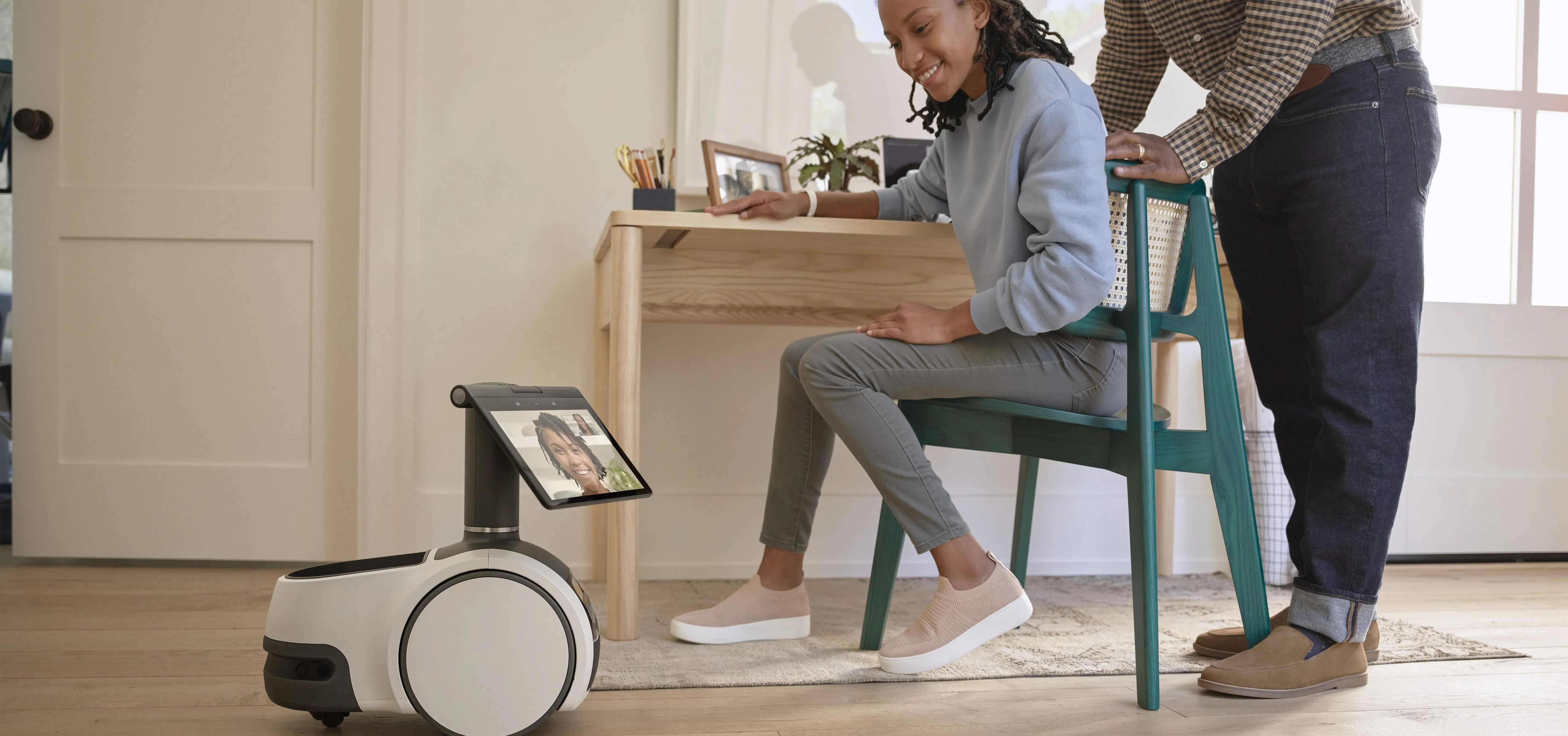 A woman sitting at a desk with a robot providing remote interaction.