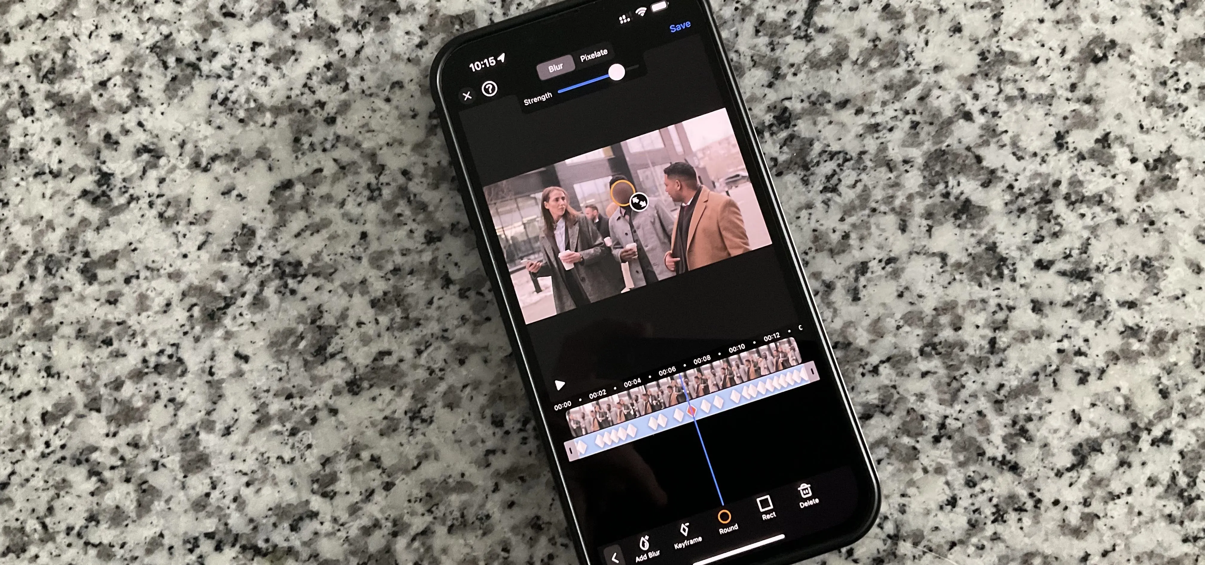 Smartphone displaying a video editing application on a granite surface.