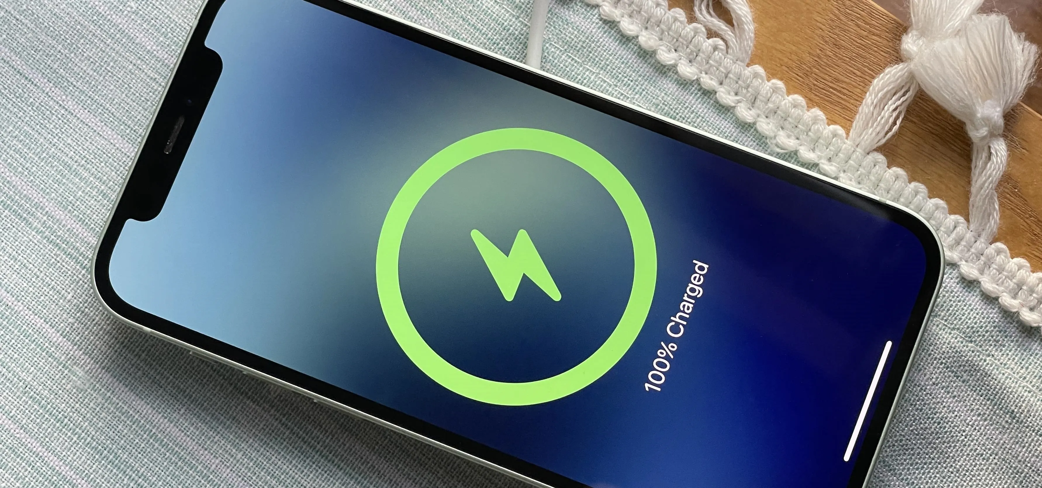 Smartphone displaying charging status at 100% with a lightning bolt icon.