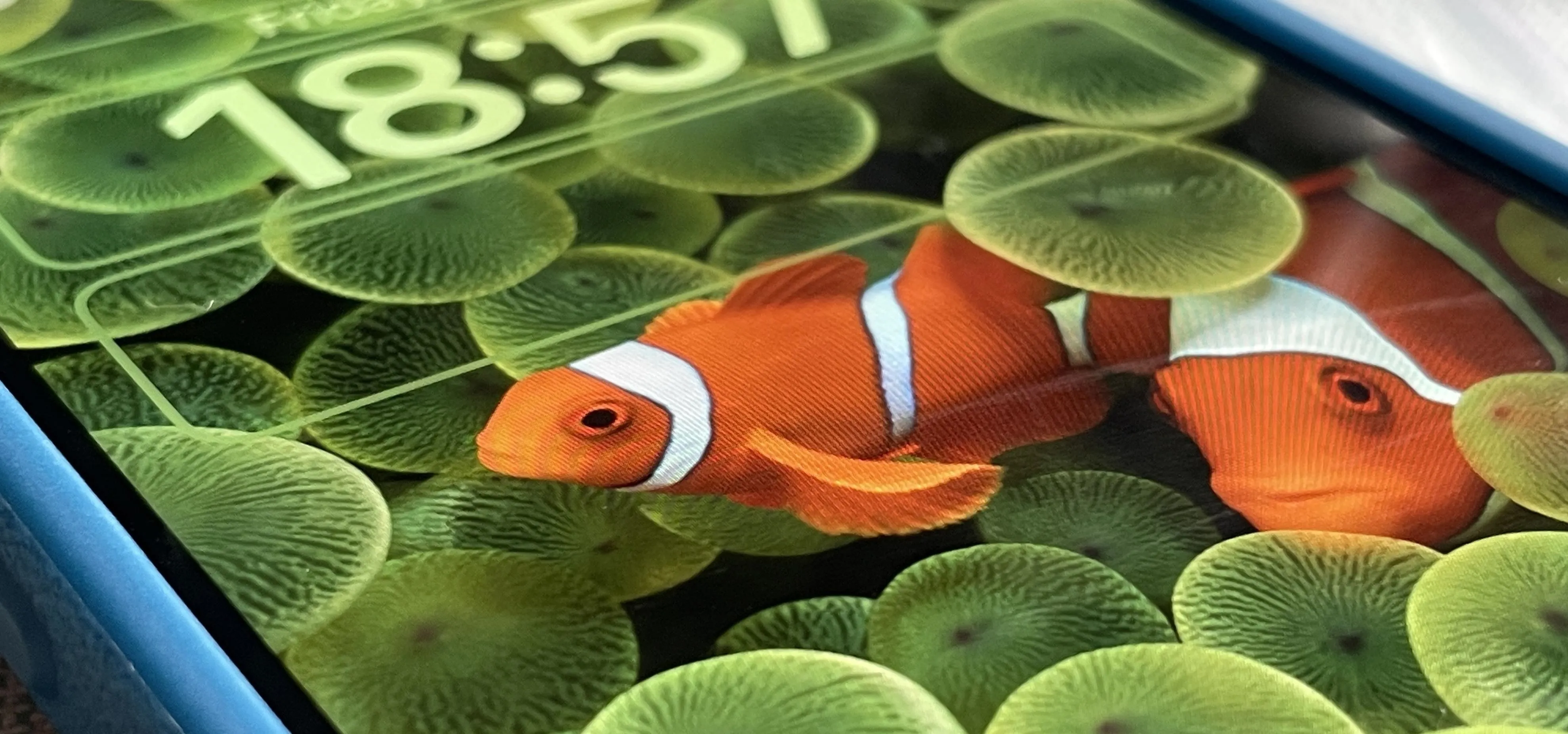 Clownfish swimming among green bubbles on a smartphone screen.