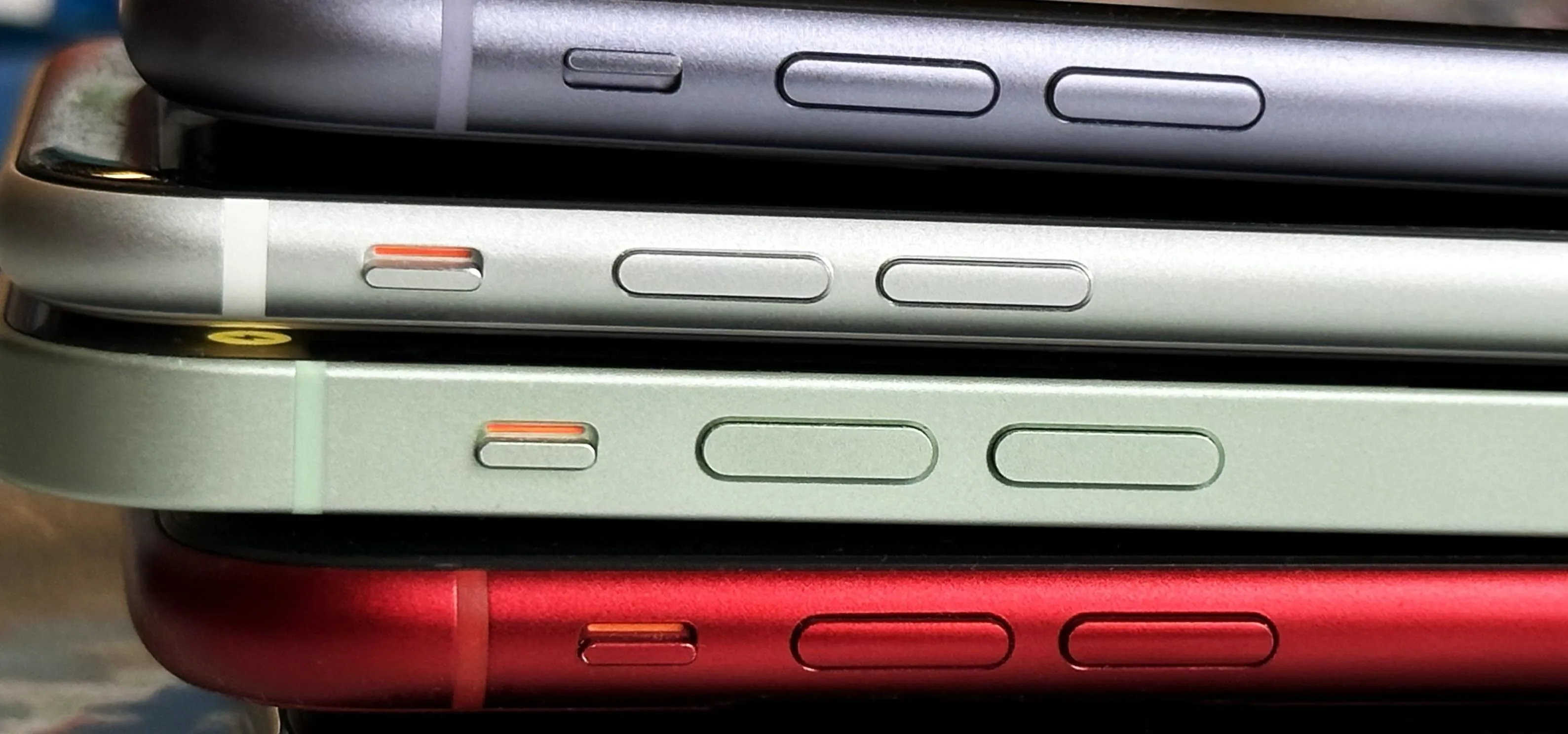 Stack of smartphones in various colors with visible side buttons.