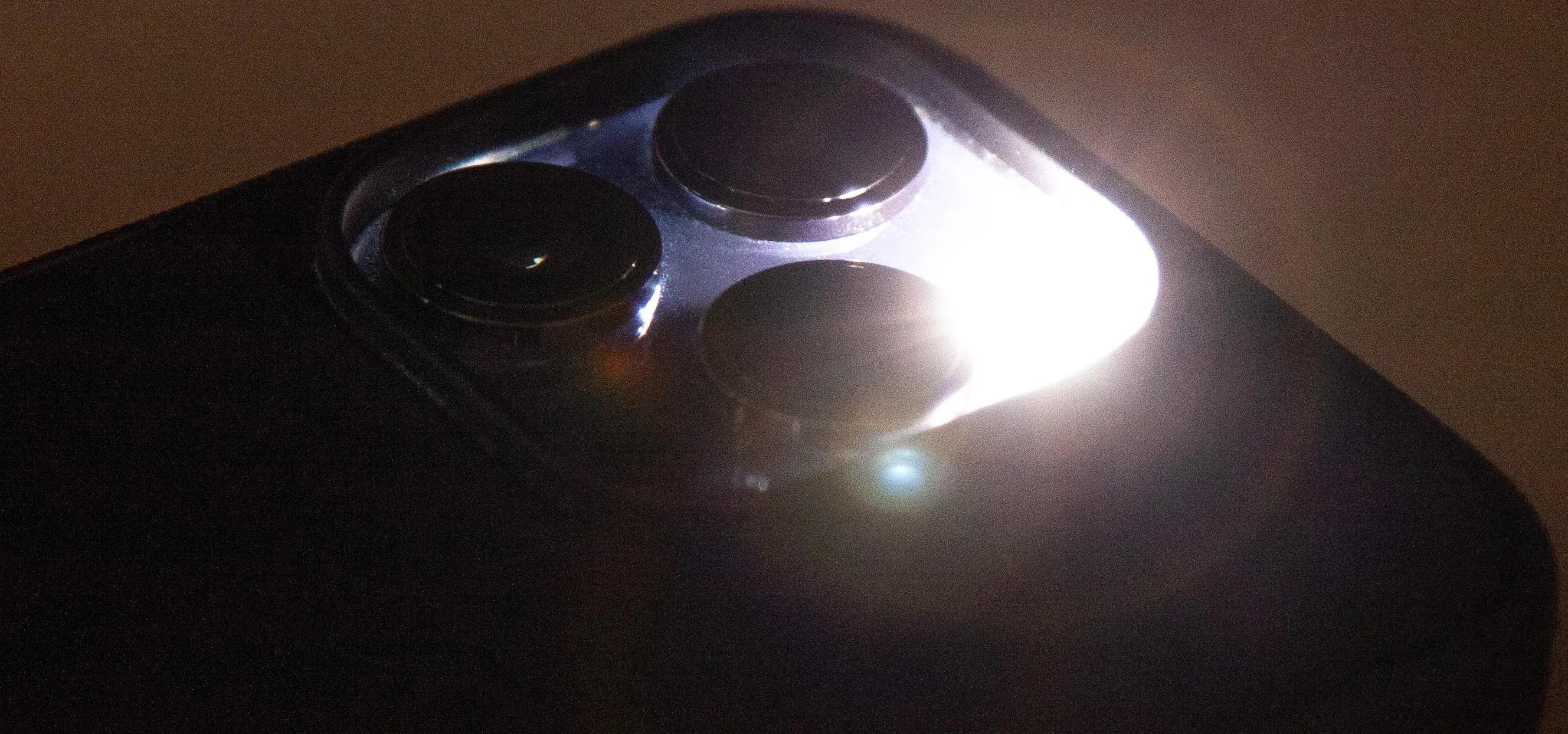 Close-up of a smartphone camera module with reflections and lens glare.