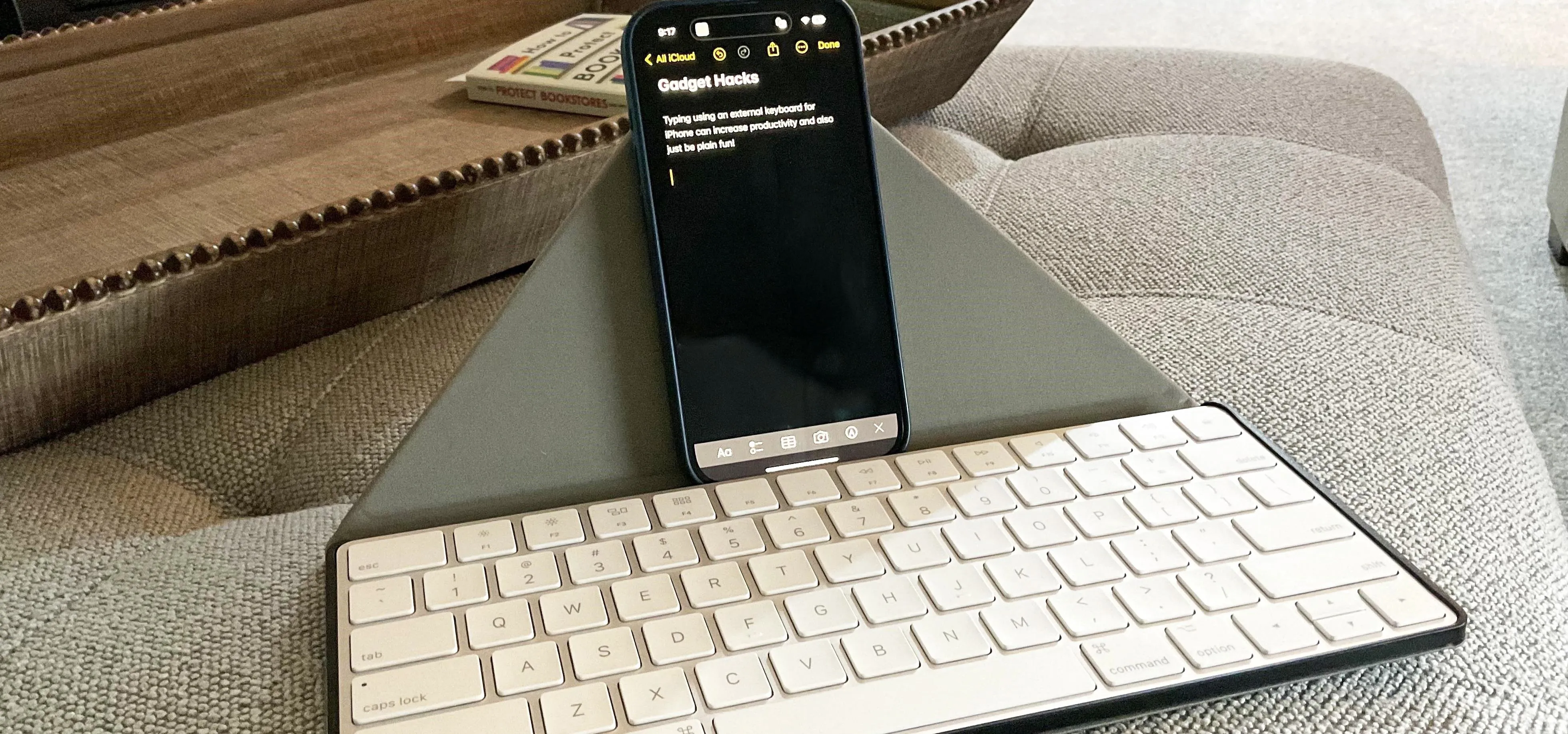 Smartphone propped up on a stand with a wireless keyboard on a couch.