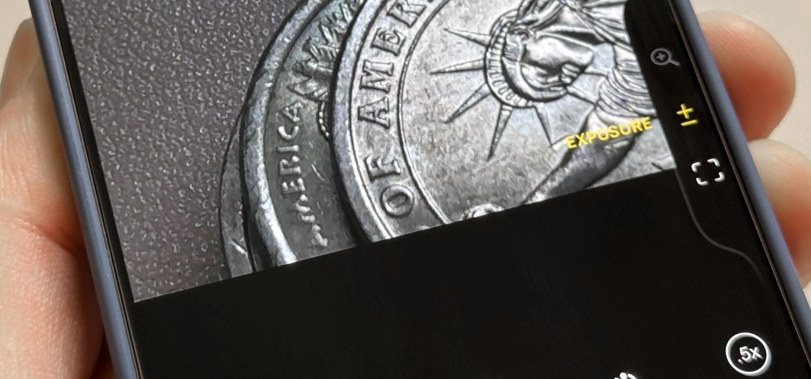 Close-up of a coin being held against a textured background.