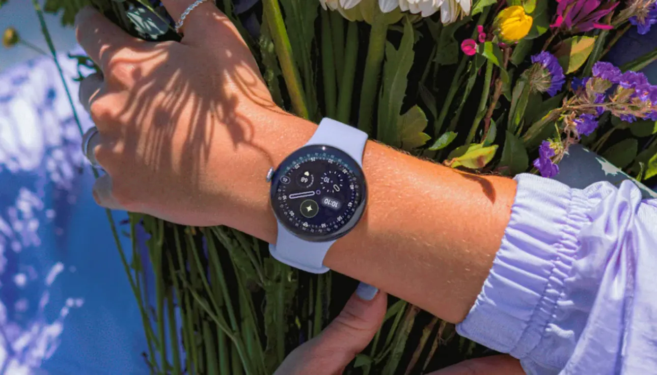 Person wearing a Google Pixel Watch 4 with a light-colored band while holding a bouquet of flowers