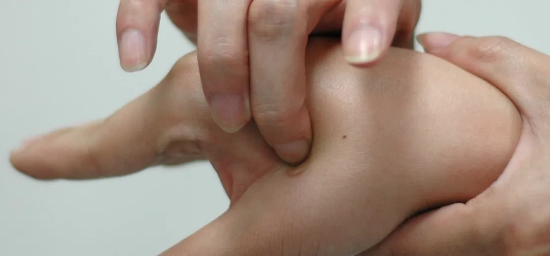 Finger pressing on skin to demonstrate a acupressure technique.