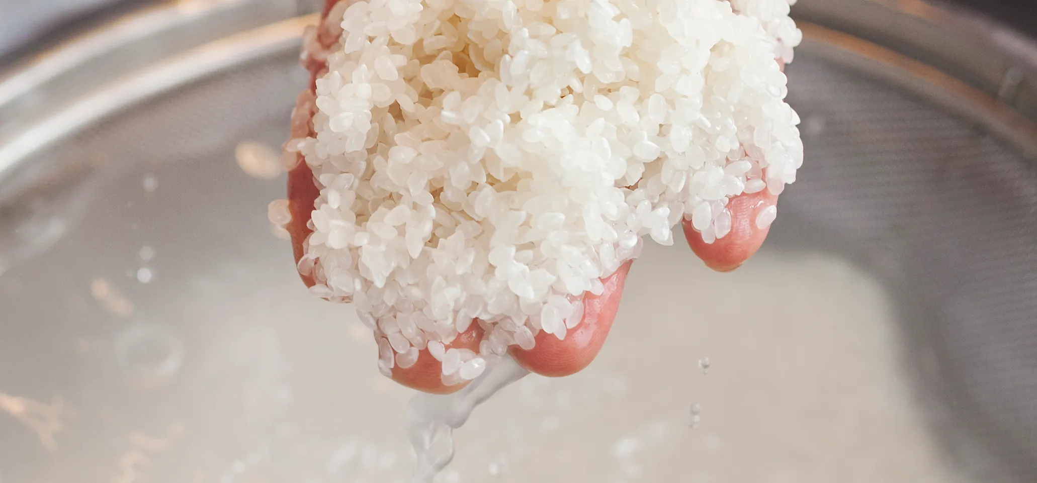 A chef working in a small commercial kitchen, an itamae or master chef making sushi. Rinsing rice for the dishes.