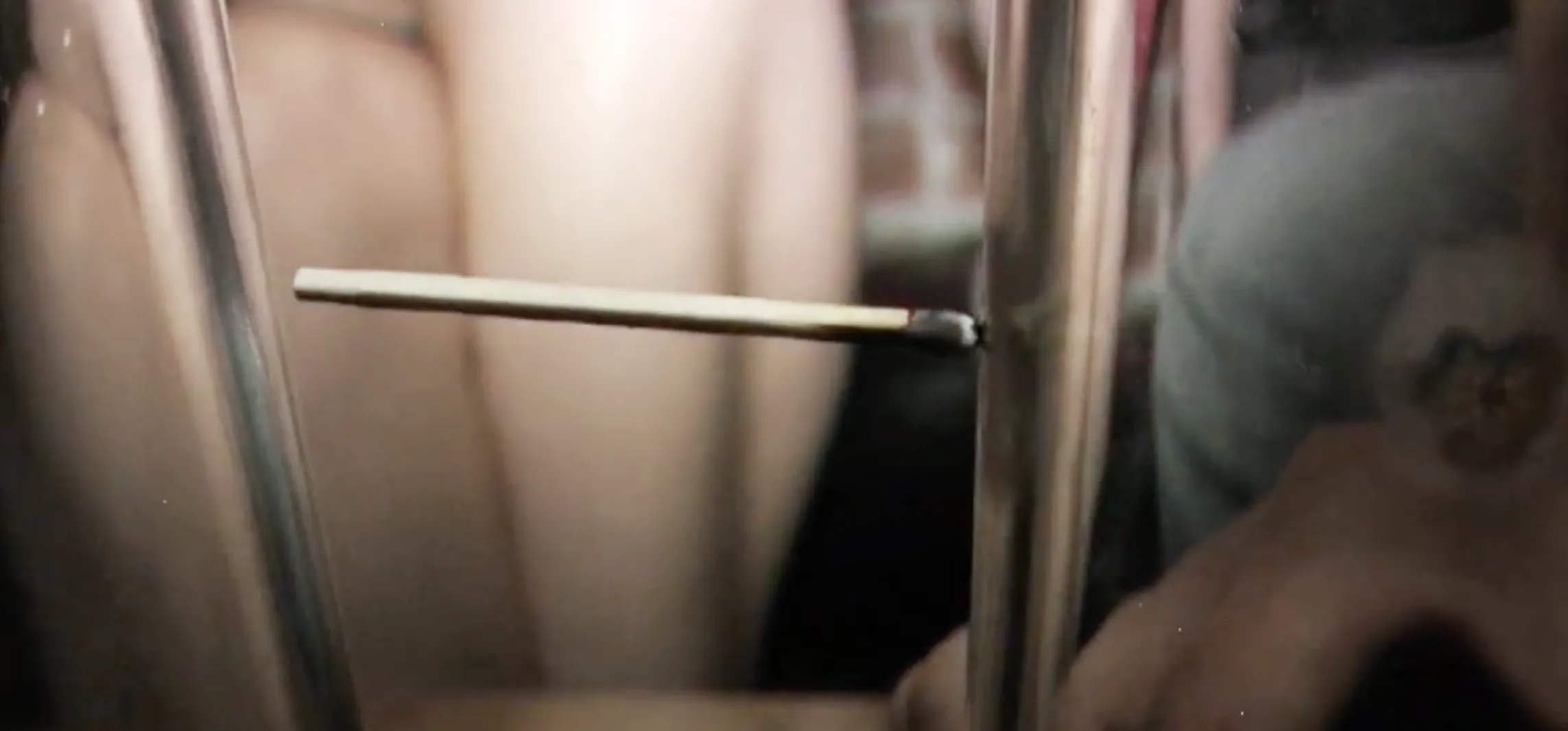 Close-up of two upside-down pint glasses on a bar table with a burned matchstick hovering between them.