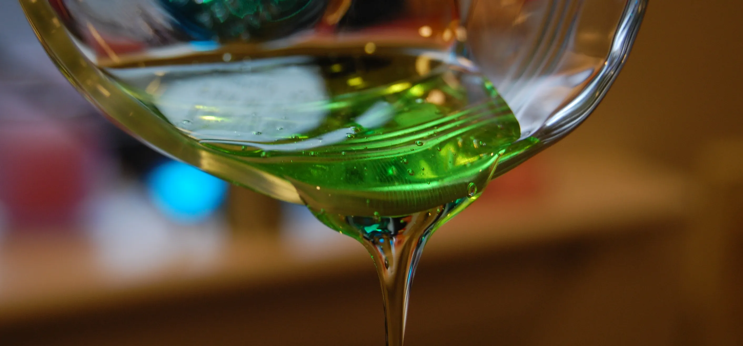 A glass measuring cup pouring out green gooey slime.