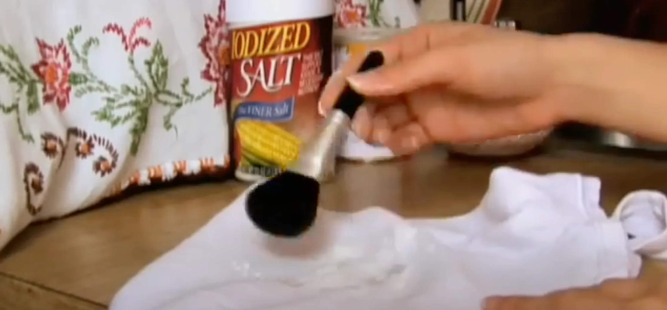 A hand dusting on a DIY cleaning solution on a greasy white piece of fabric.
