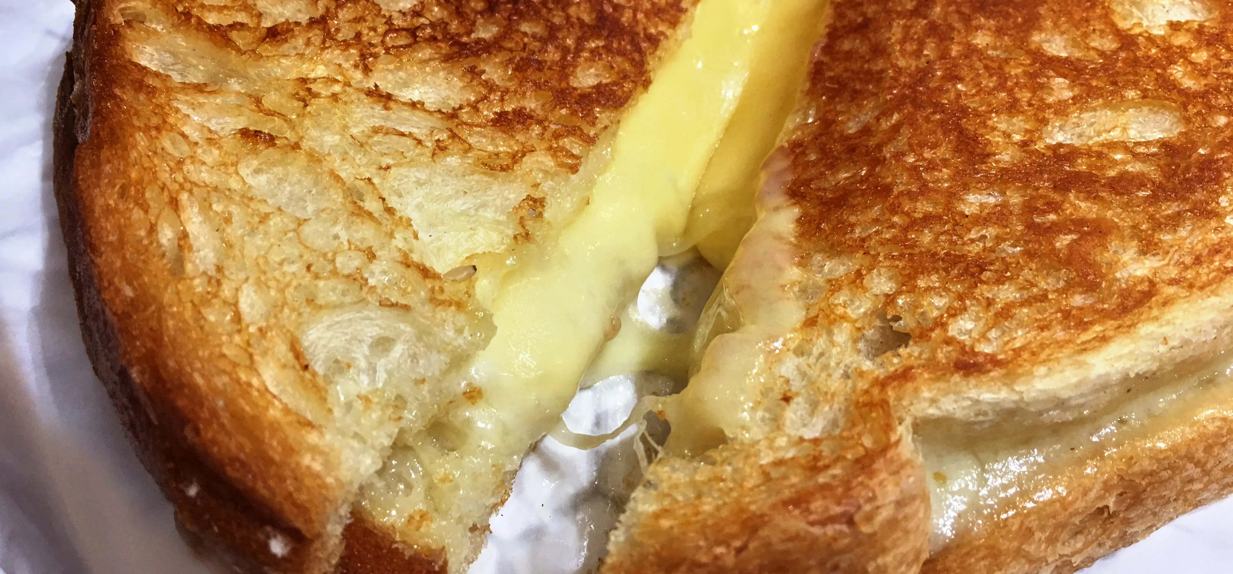 Closeup photo of a grilled cheese sandwich sliced in two and pouring out melted cheese.