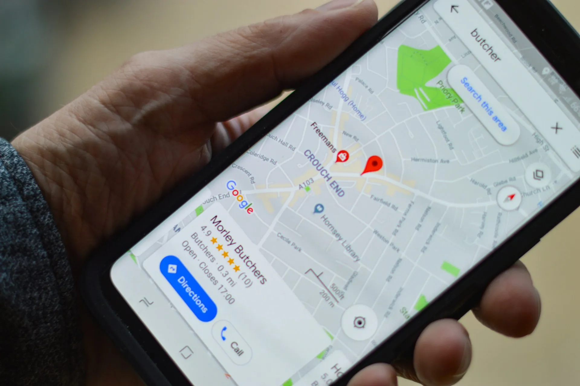 Person holding a smartphone displaying Google Maps directions and a pinned location