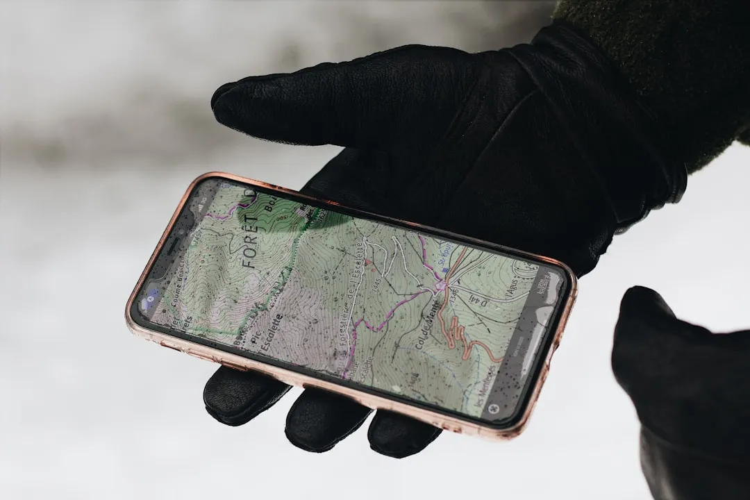 A hand holding a smartphone displaying a smiling person with a blurred outdoor setting.