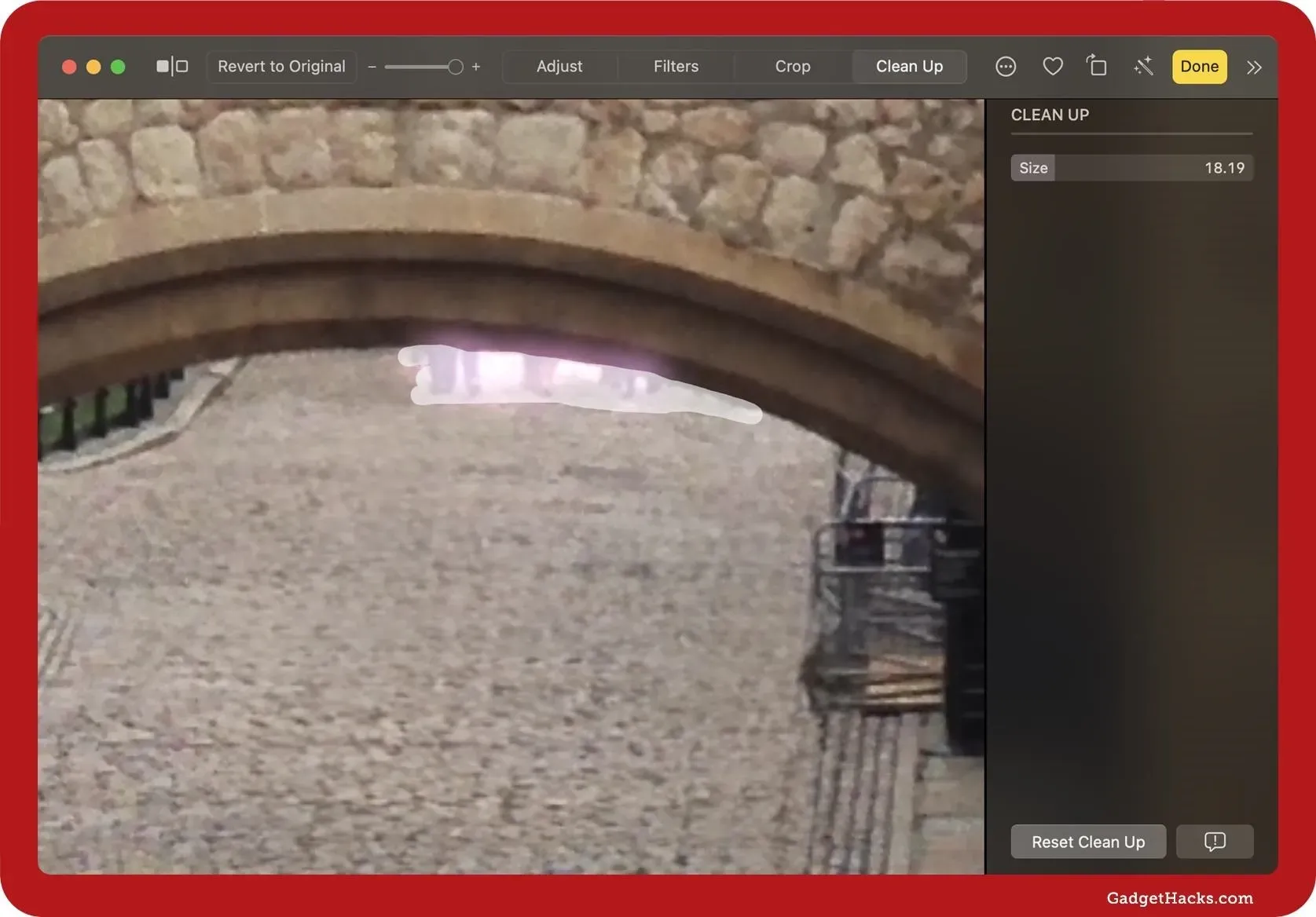Zoomed-in view of the ‘Clean Up’ tool on macOS Photos app showing brush strokes removing people from under a castle archway.