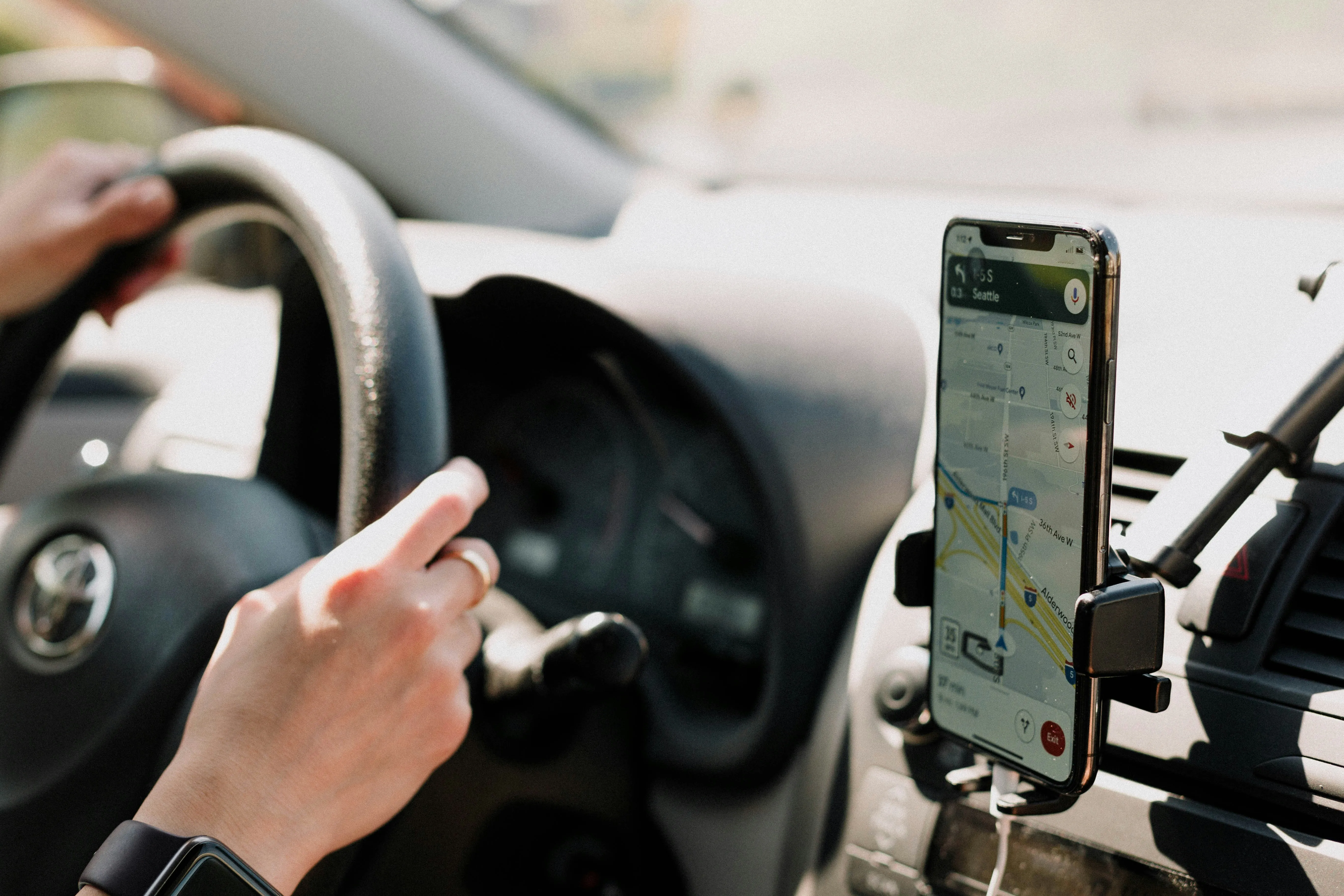 Driver using Google Maps navigation on a smartphone mounted inside a car