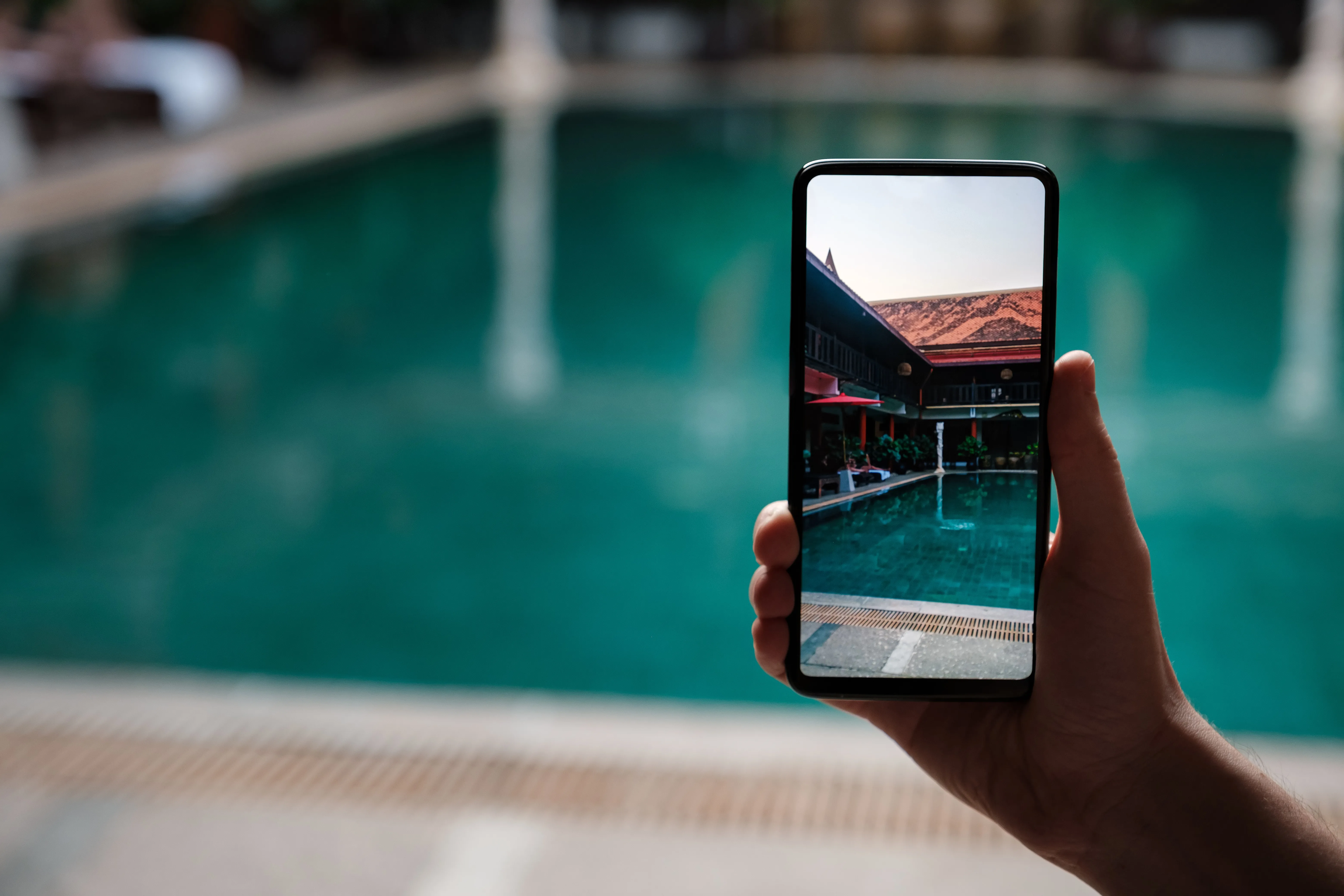 image of a phone being held up in front of a pool