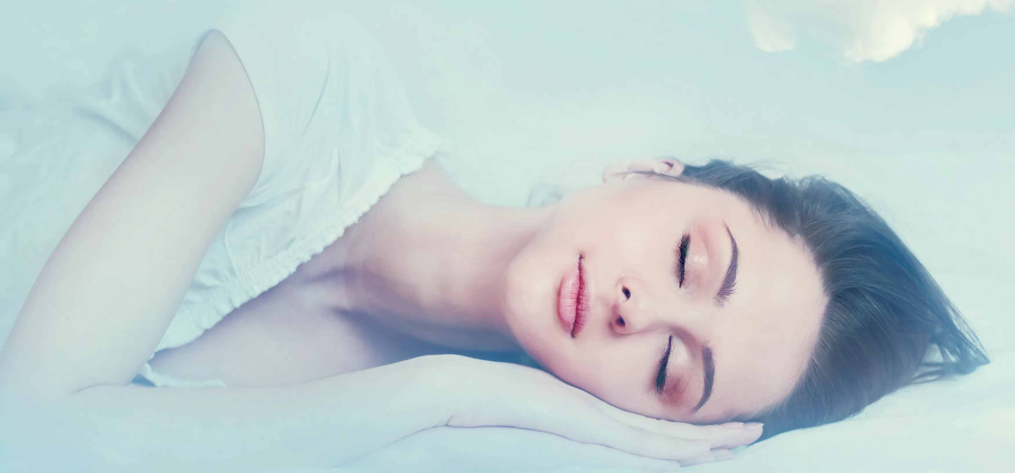 Beautiful young girl sleeping on her side and dreaming in the clouds.