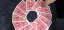 Hands execute 12 o'clock card trick, arranging red Bicycle playing cards in a circle on dark fabric, center hole highlighting clock illusion.