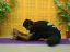 Man doing a seated forward bend yoga pose on a purple mat.