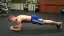 Man performing a plank exercise in a gym setting.
