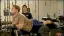 Man performing an exercise on a bench with a trainer observing.