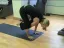 Woman practicing yoga in a crow pose position on a mat.