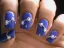 Nail art featuring blue polish with decorative white embellishments.
